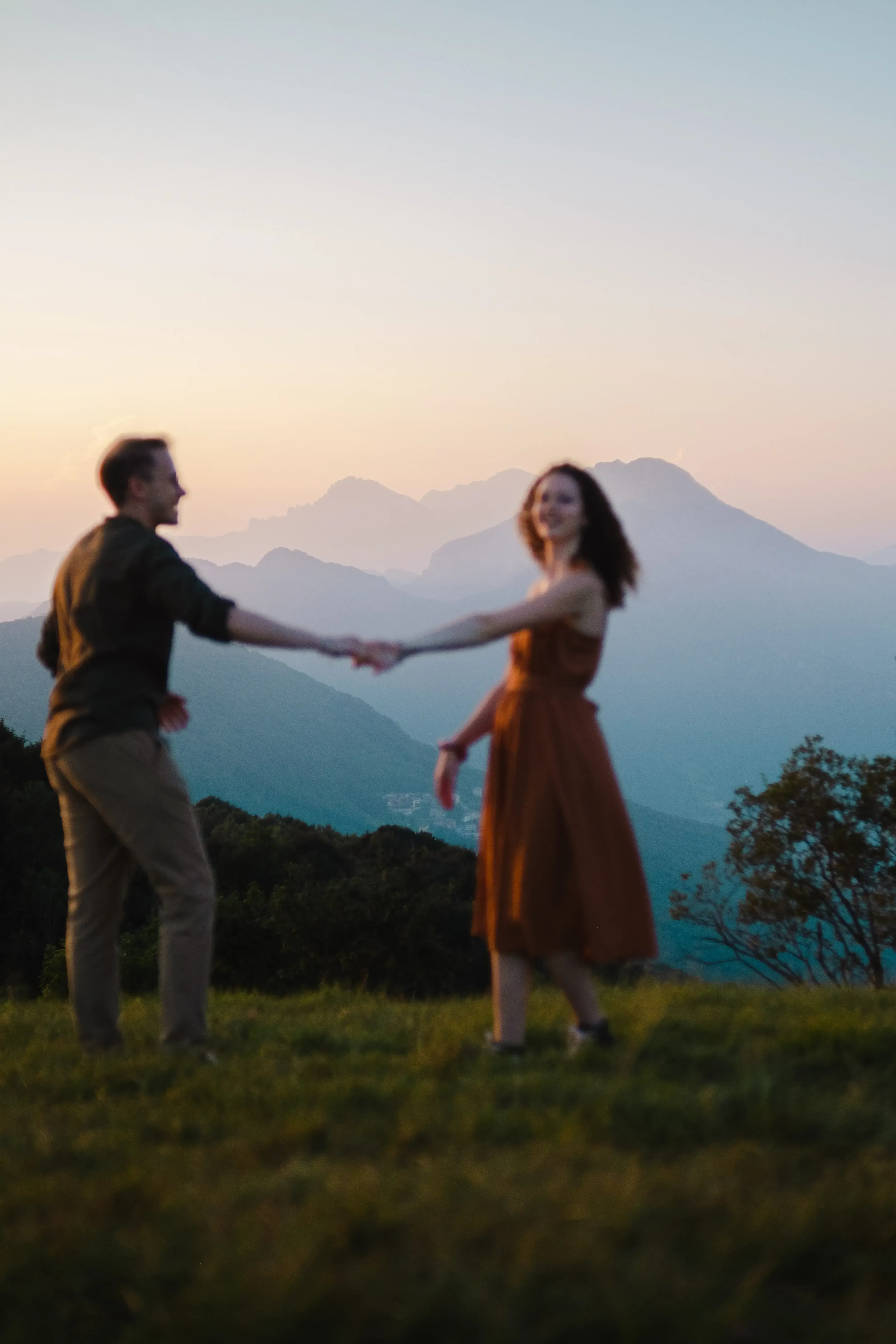 Nicolò and Greta laughing and dancing freely in the mountain meadow.