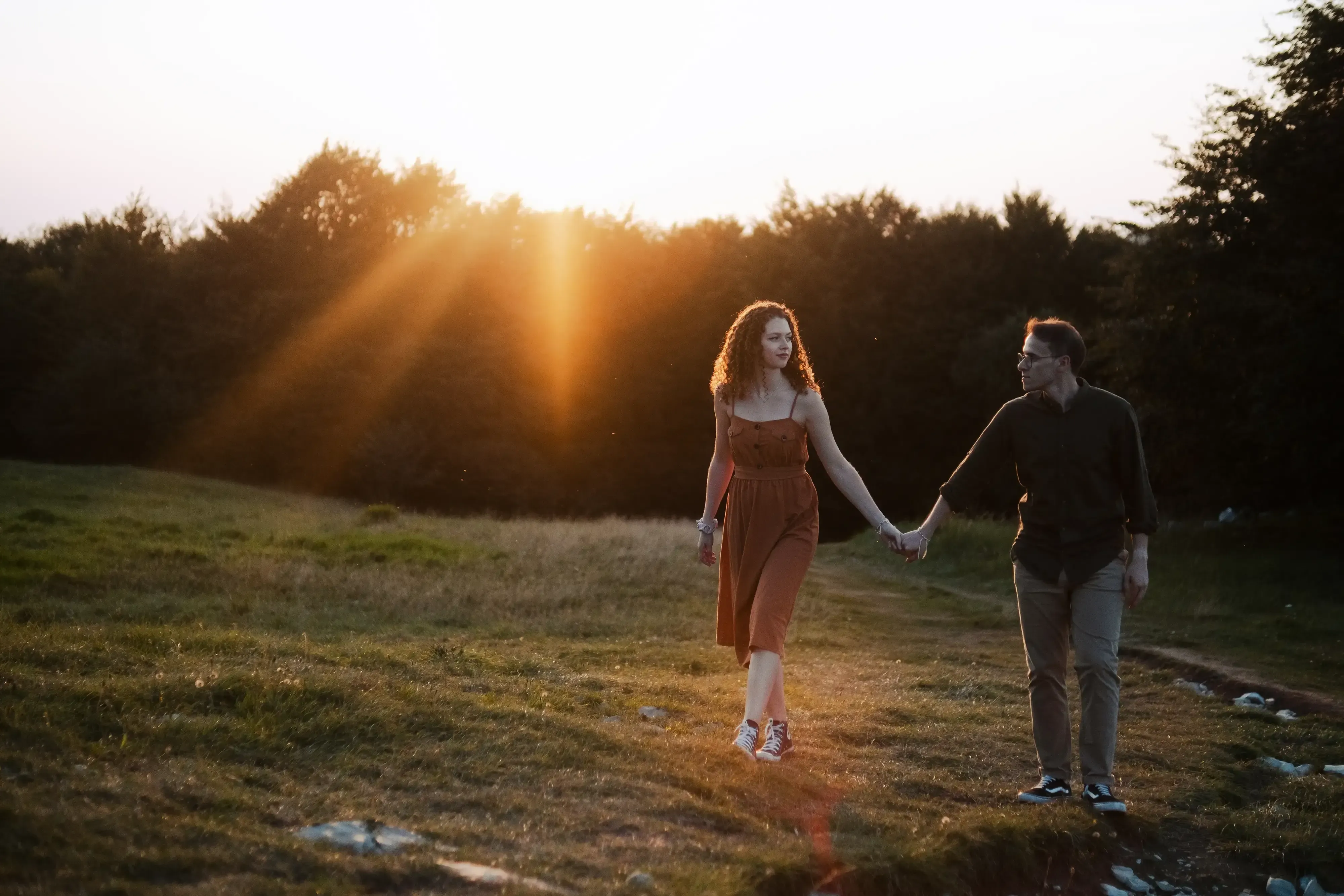 The couple walking hand-in-hand along a scenic mountain trail.