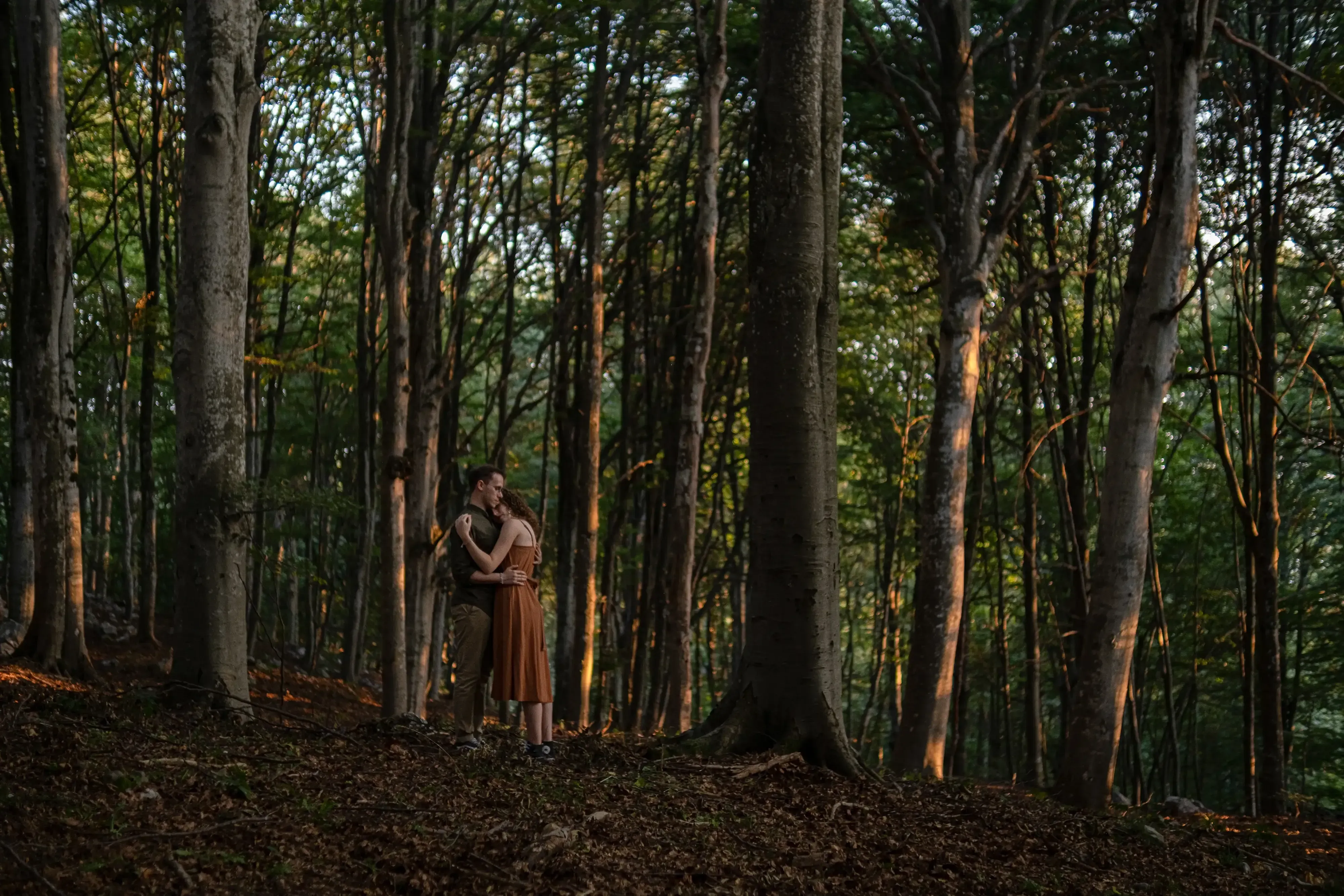 Long shot of Nicolò and Greta standing close together in the expansive mountain landscape.