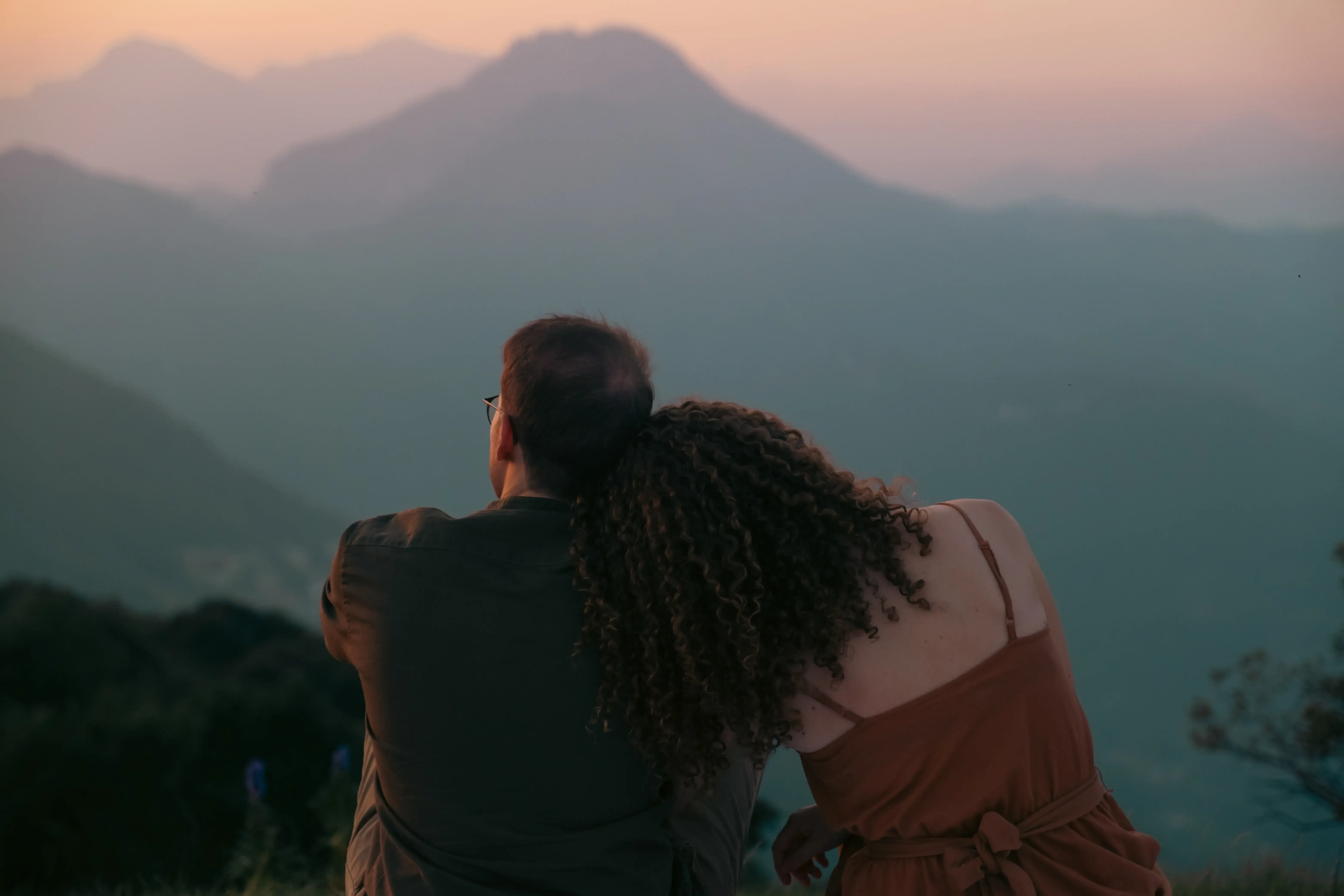 Nicolò and Greta viewed from behind, watching the horizon with Greta resting her head on him.