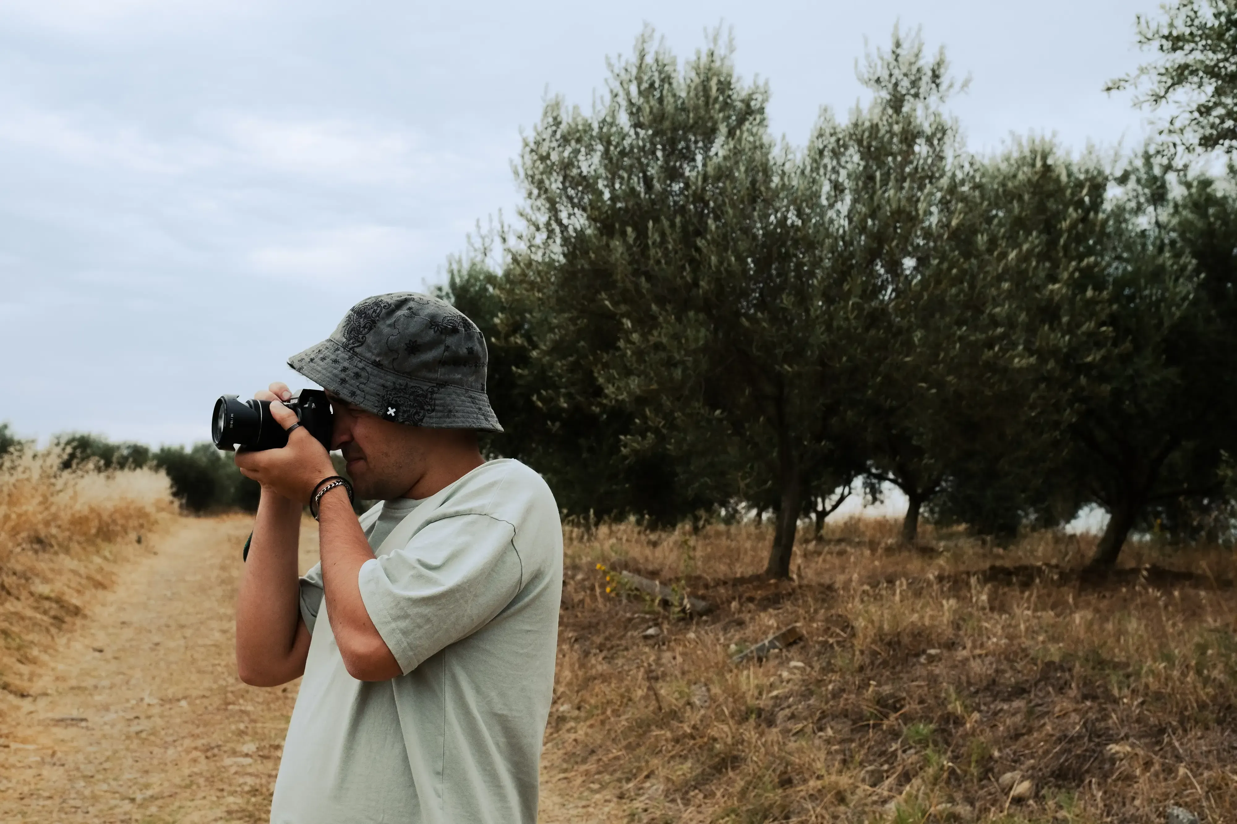 Ieser taking a photograph in a scenic, rolling field or rural area of the Romanian countryside.