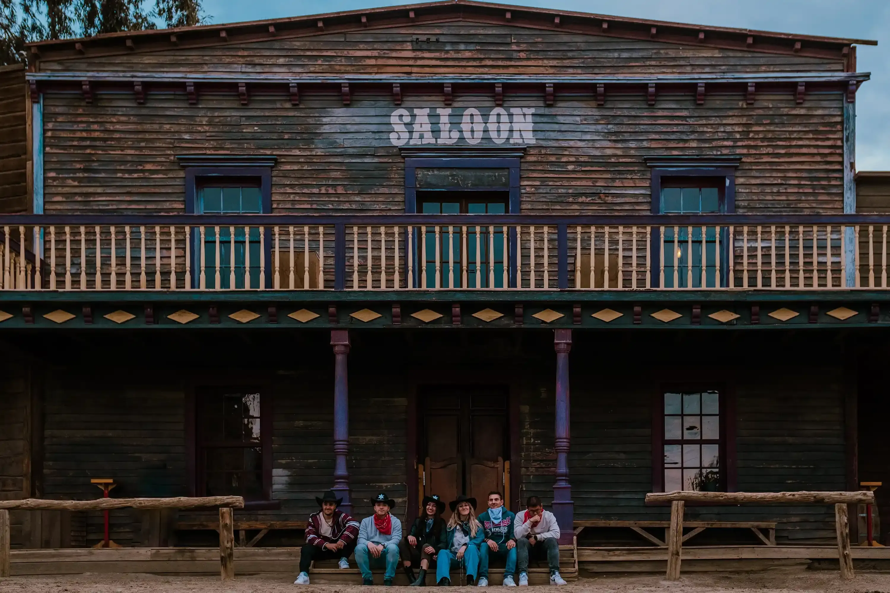 A group of friends sitting together on a bench or porch in front of the saloon.