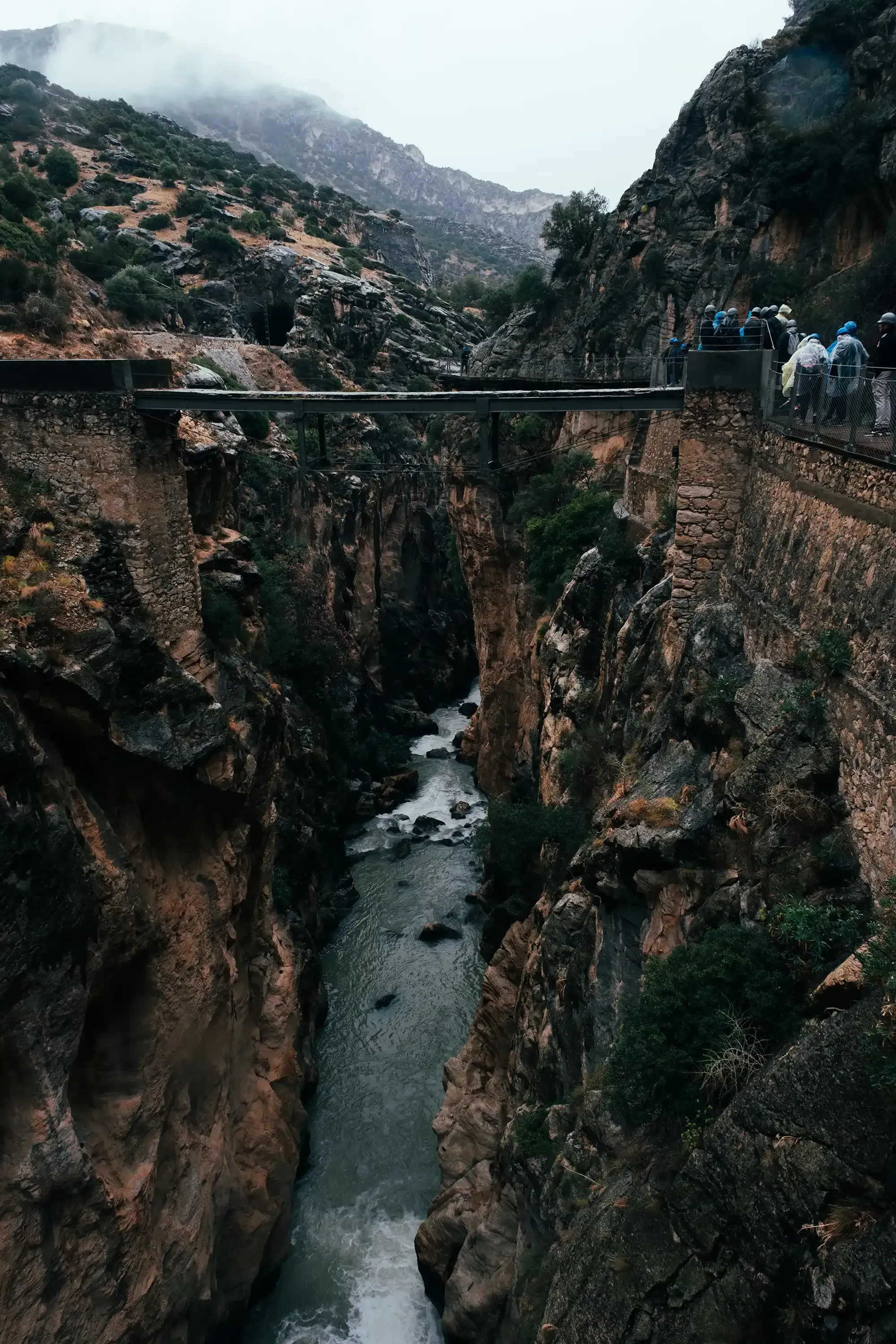 The historic, original wooden and metal pathway of the Caminito del Rey, now derelict and visible below the new, secure bridge.
