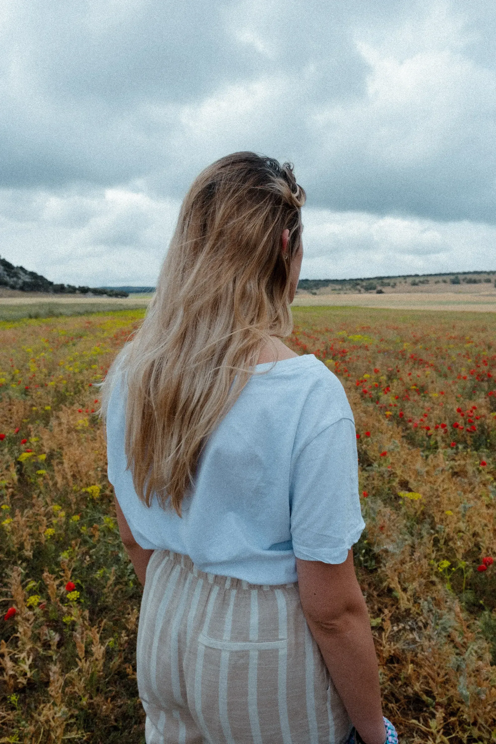 Letizia viewed from behind, standing among the rolling fields of Andalusia.