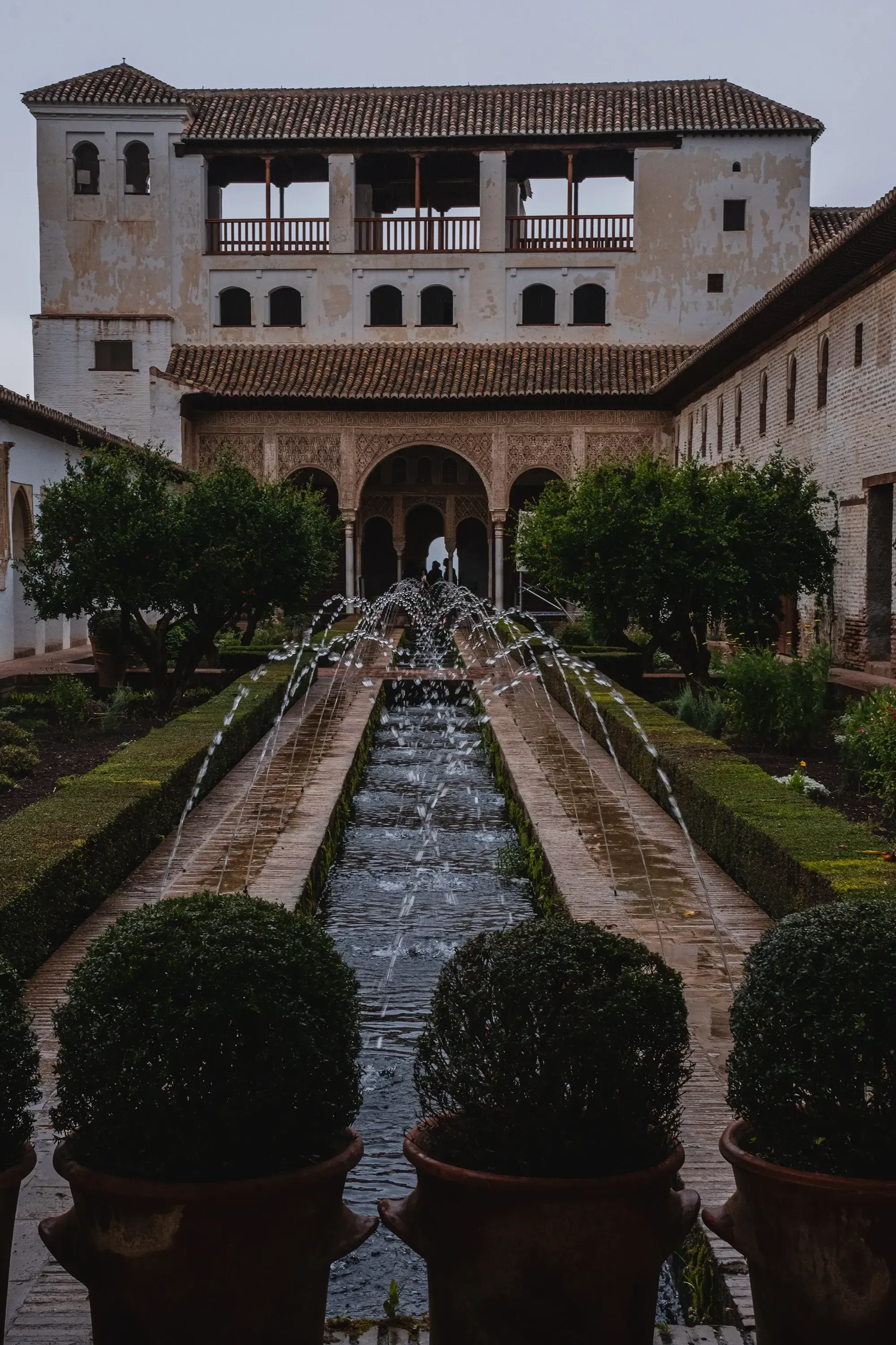 Inner view of the Alcázar palace courtyard pool during light rain.