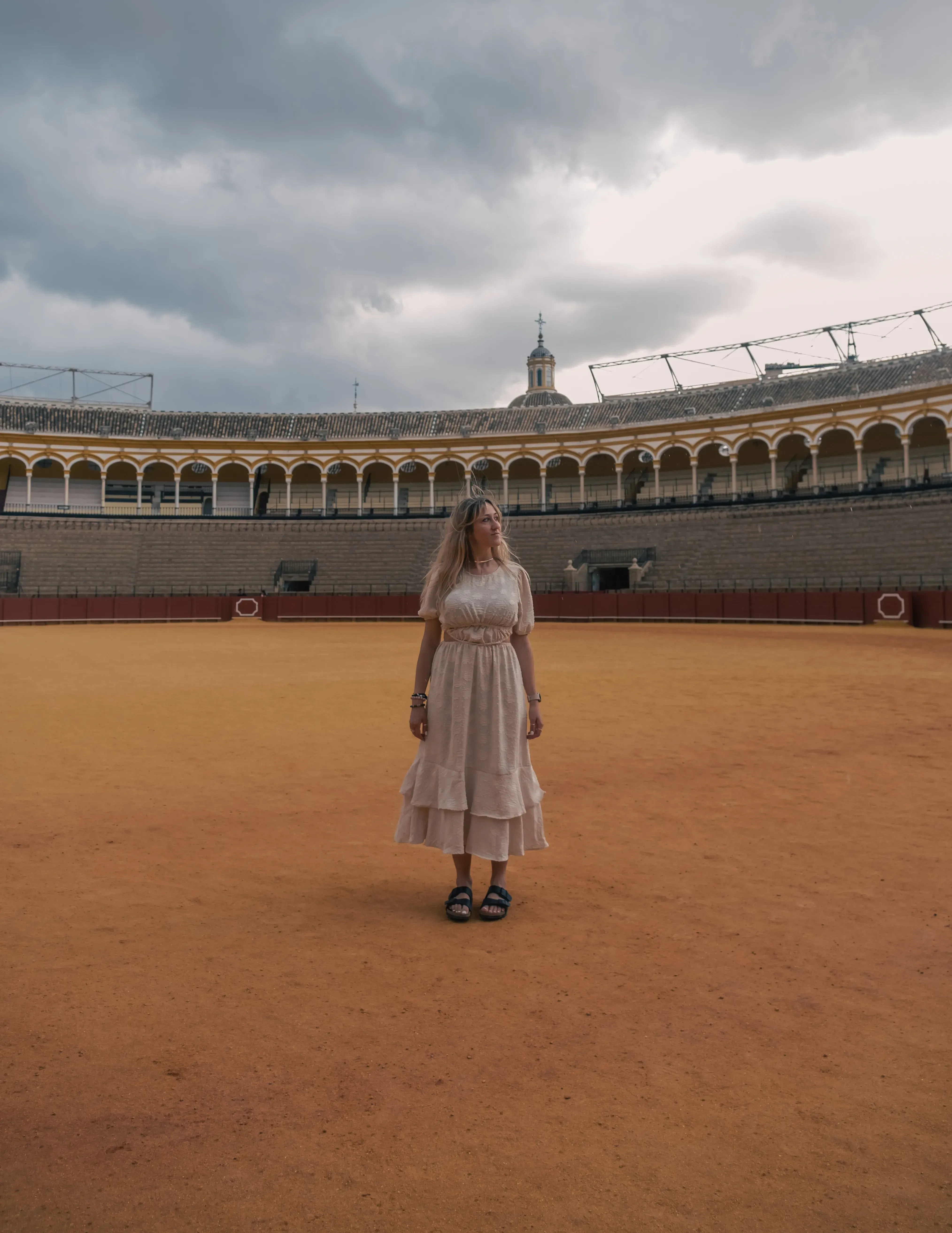 Letizia standing in the center of the bullring (Plaza de Toros) in Seville.