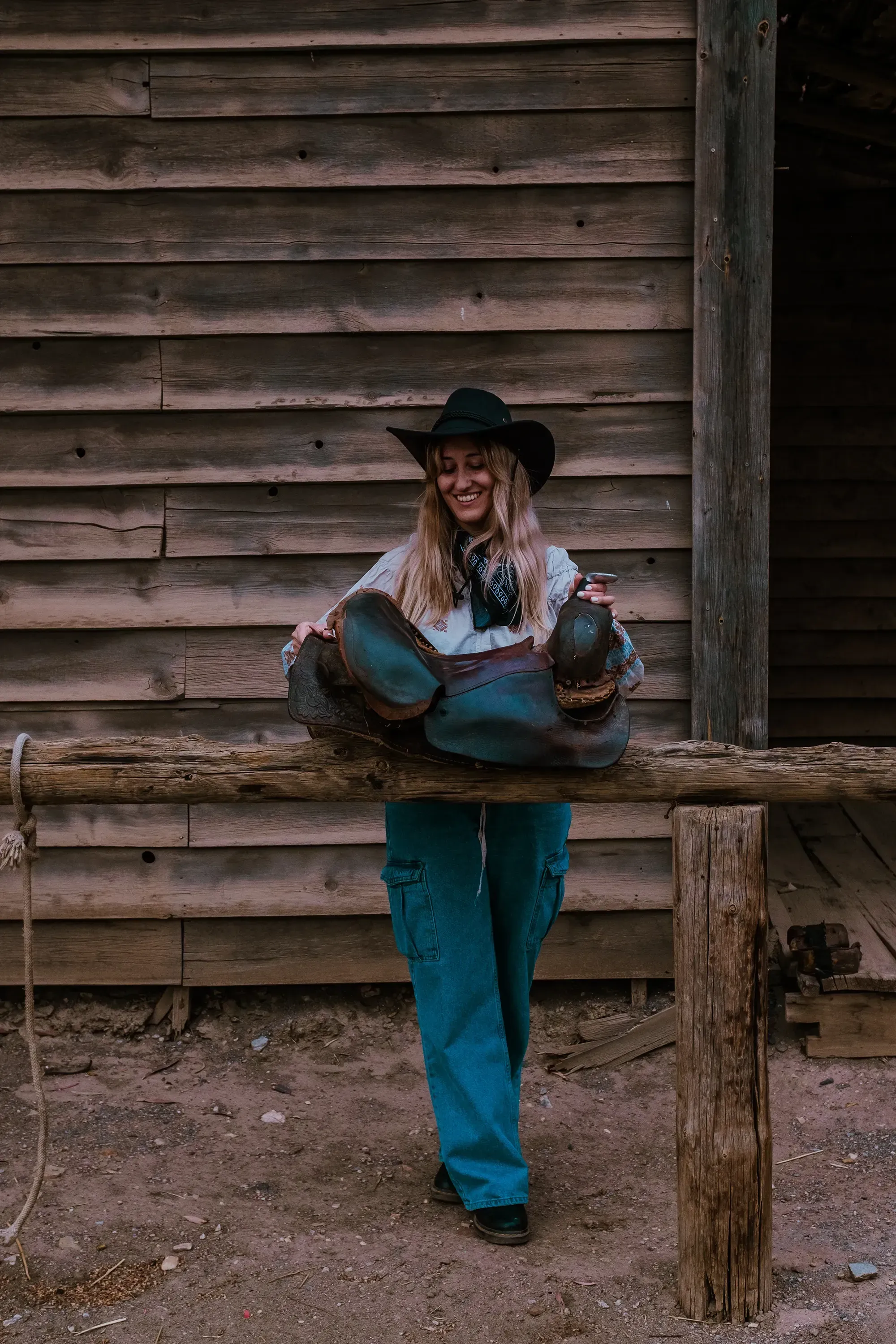 Letizia adjusting or moving a horse saddle in the western-style town of Tabernas.