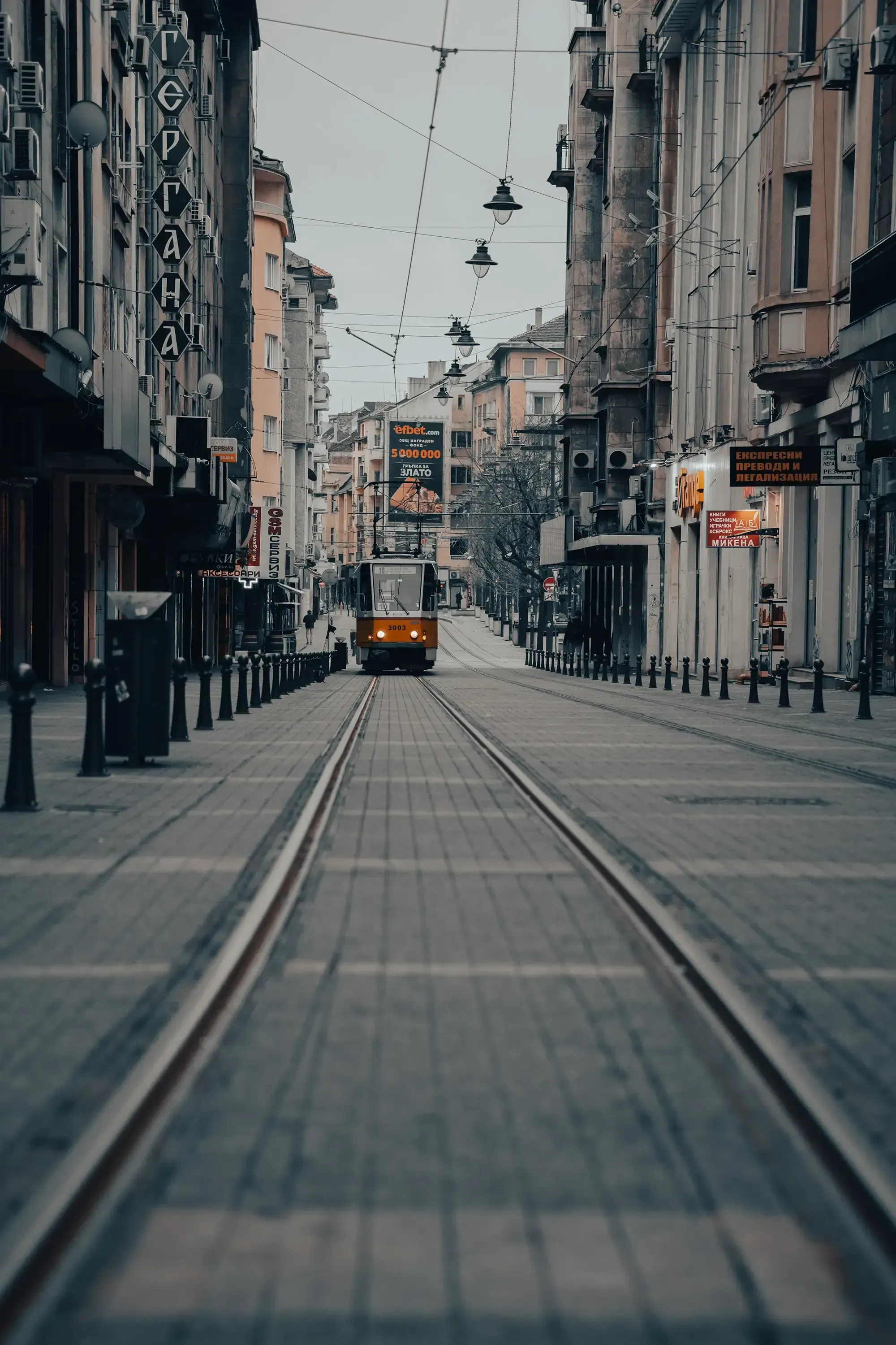 View of the tram approaching from a low perspective along the railway tracks.