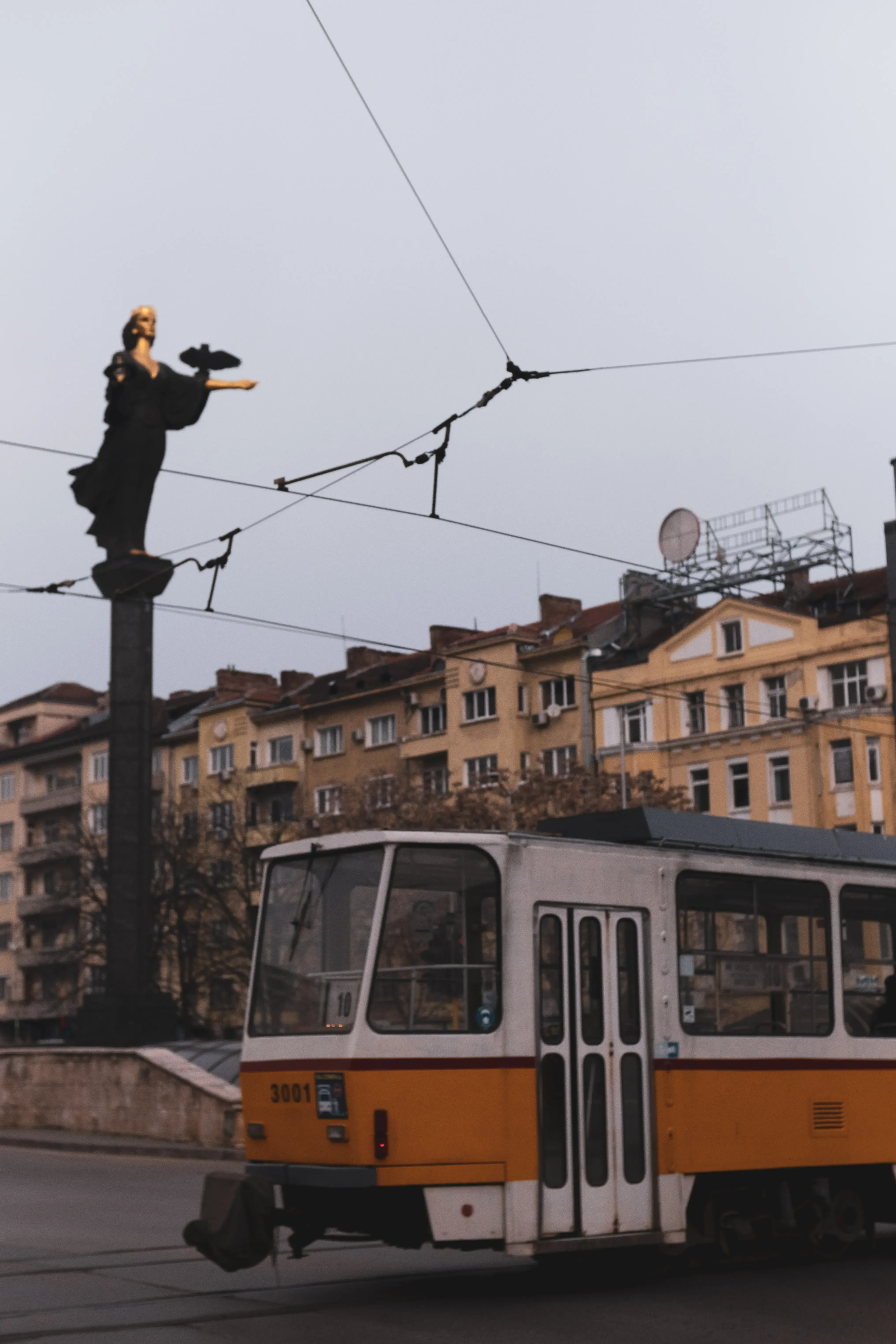 The tram passing near the tall column supporting the Statue of Saint Sofia.