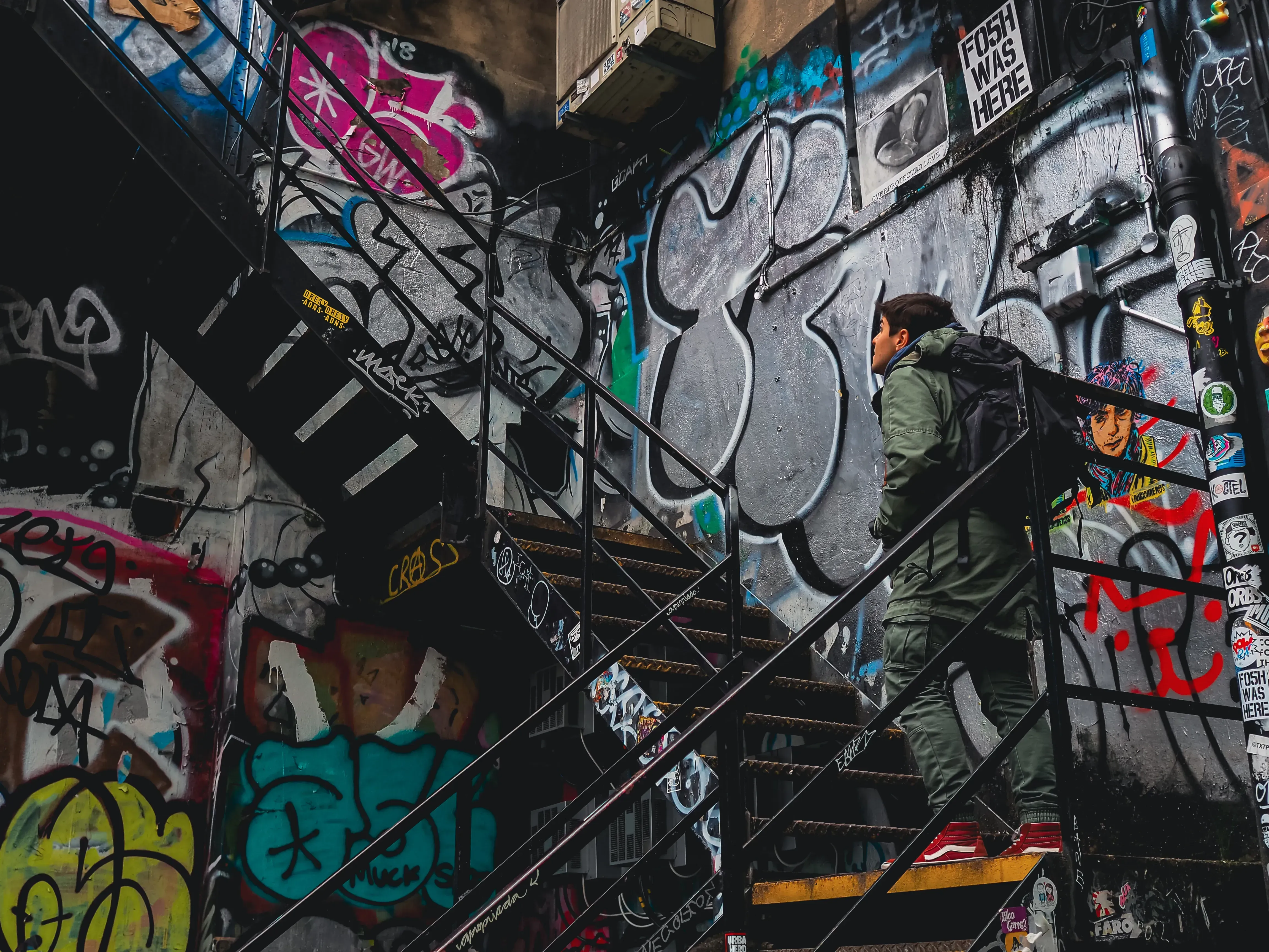 Ieser walking up a flight of stairs, surrounded by vibrant street art and graffiti in the Shoreditch district.