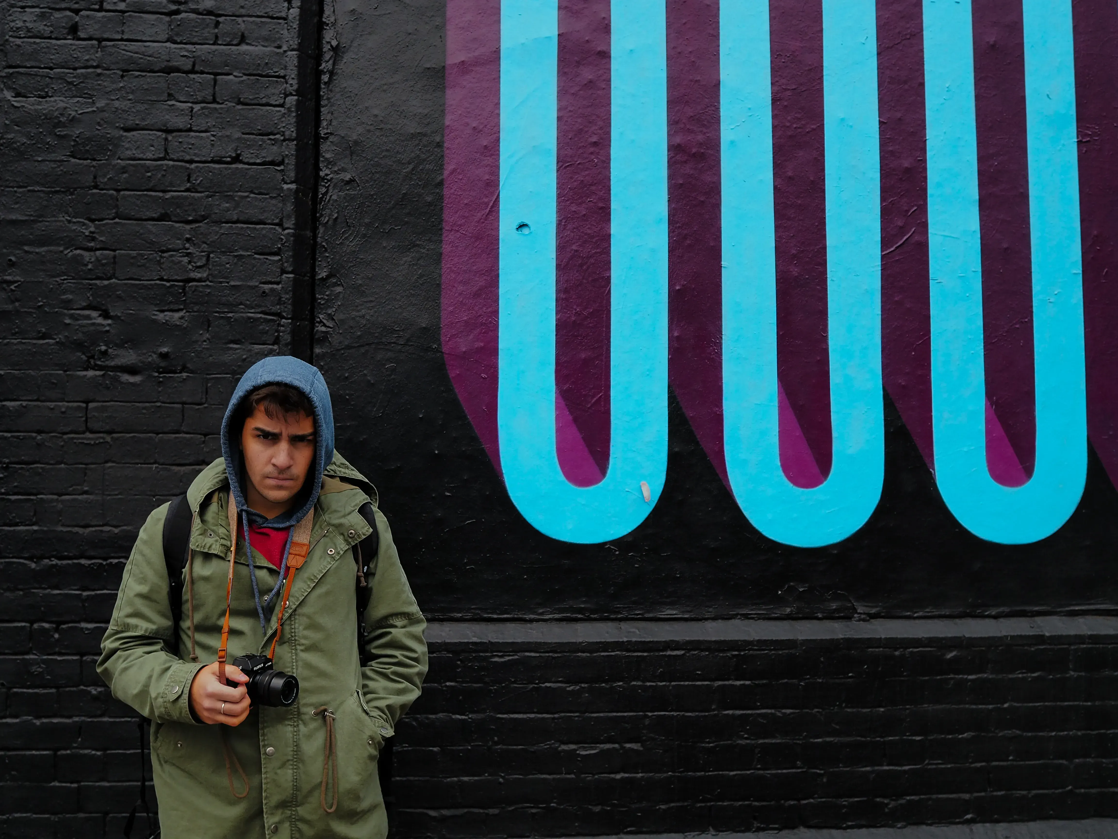 Person standing in front of a colorful, large-scale piece of graffiti art.