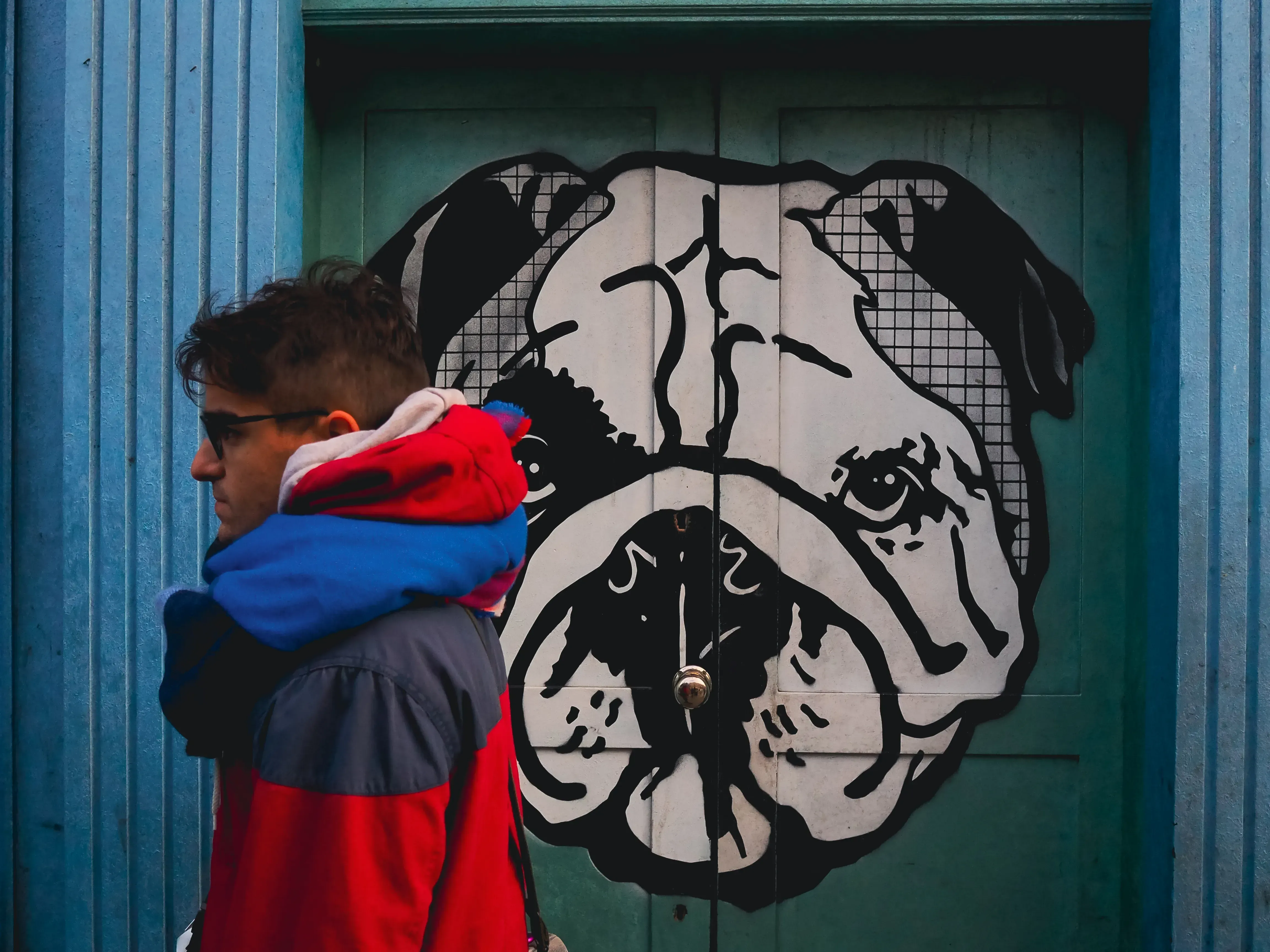 Person posing in front of a vibrant street art mural of a dog.