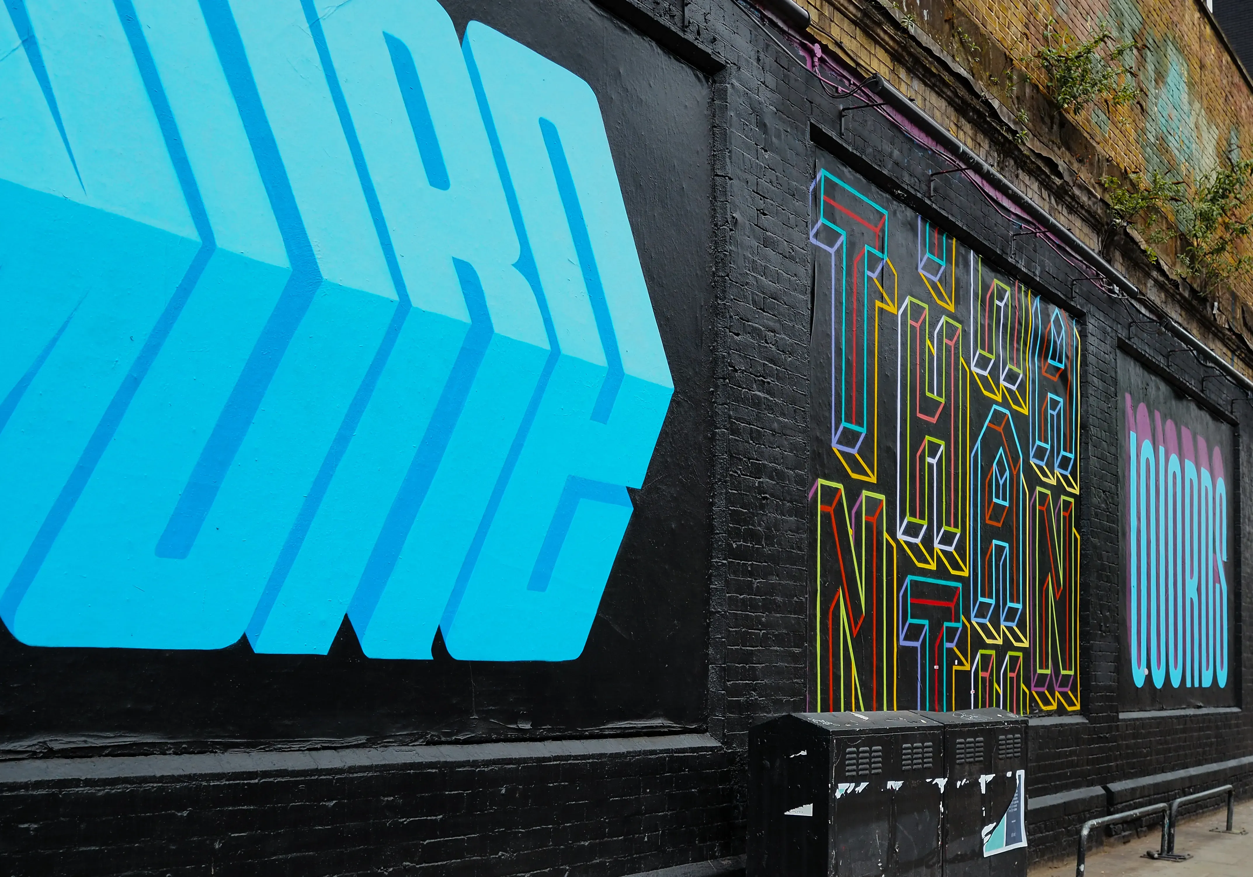 Wall covered with multiple layers of layered and abstract street graffiti.