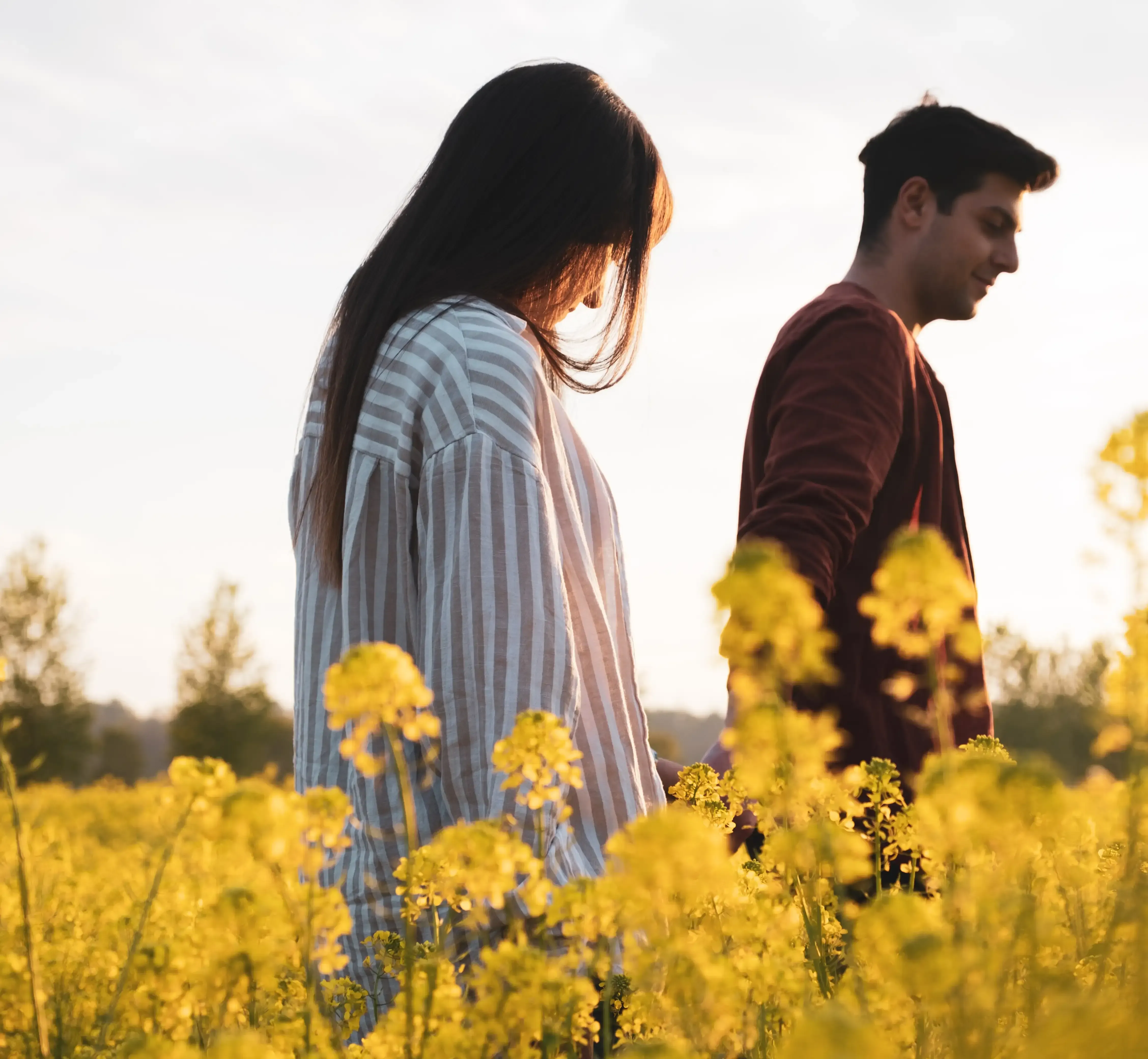 Giuseppe and Indya walking in a rapeseed field at sunset