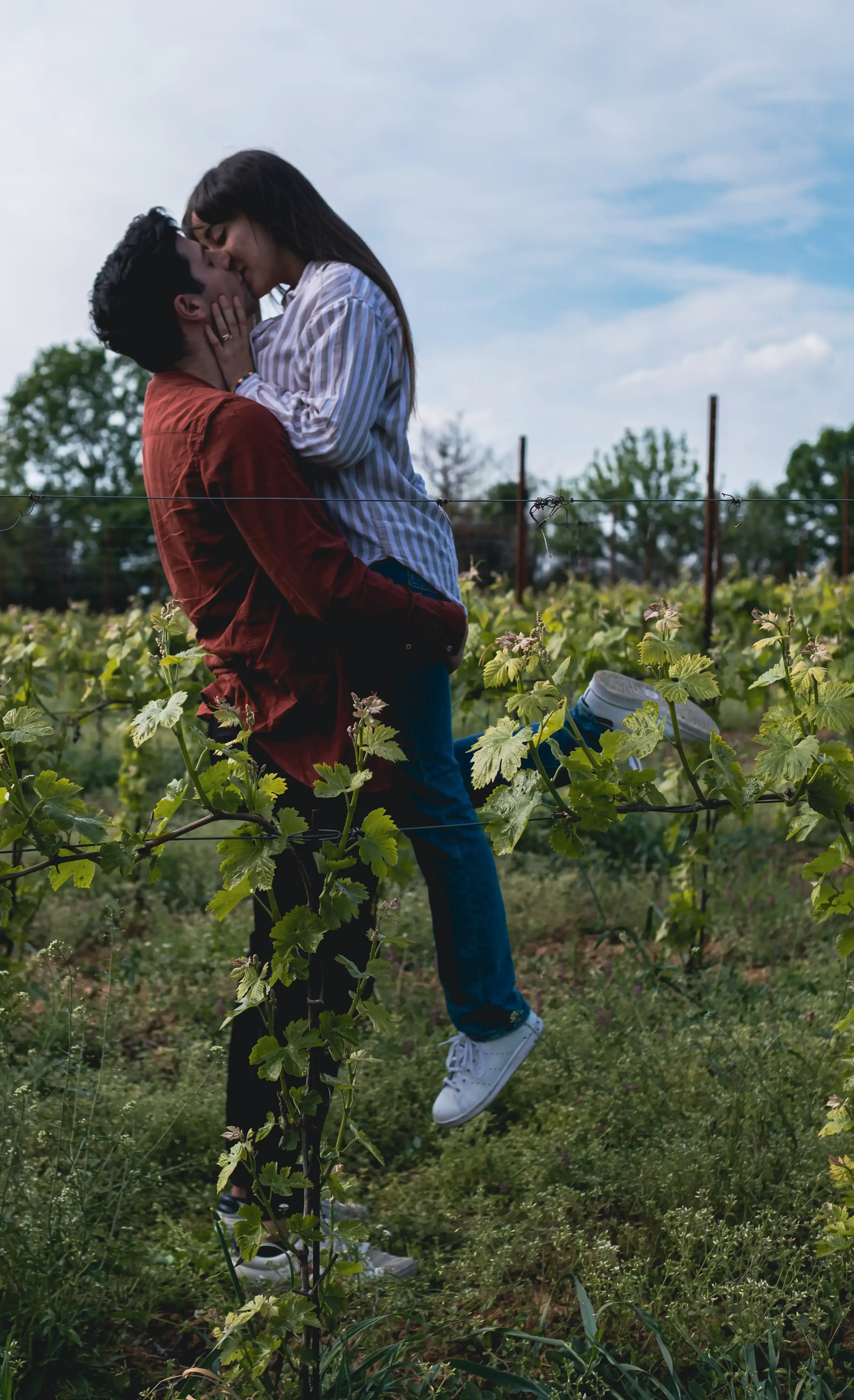 Giuseppe lifting Indya and kissing her in a scenic vineyard at golden hour.