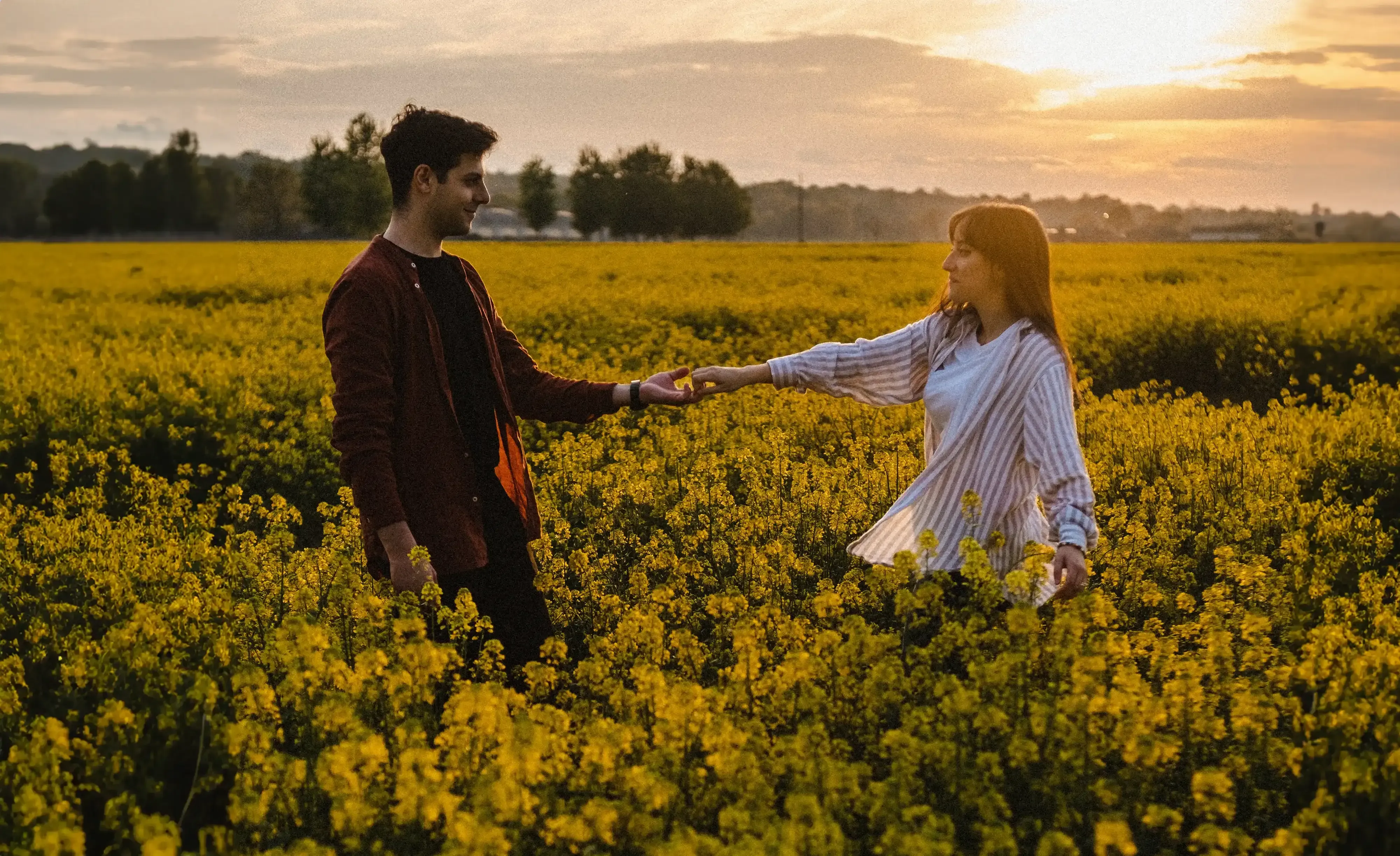 Giuseppe and Indya holding hands and dancing playfully in the wide yellow field.
