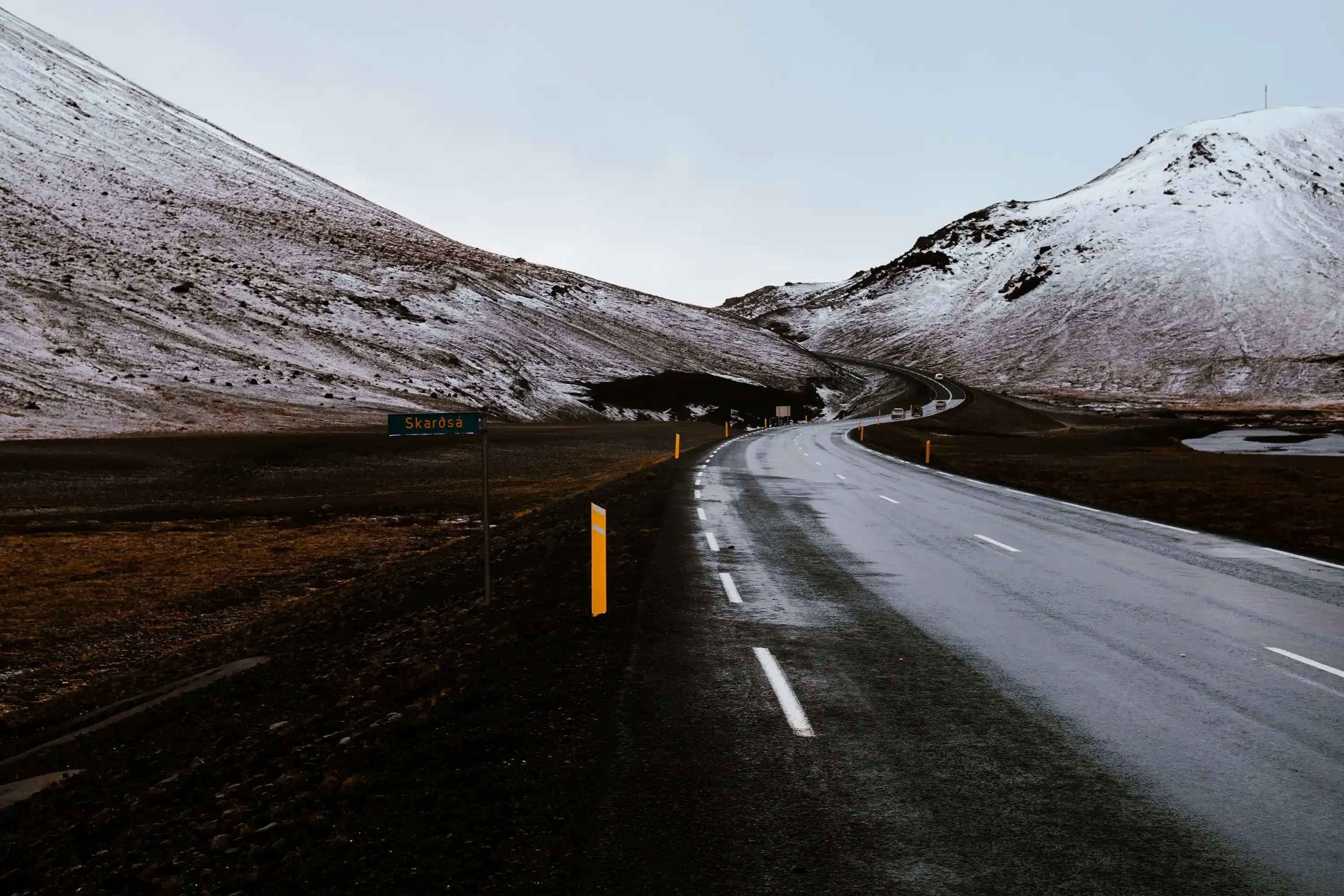 A winding road covered in snow and ice, surrounded by the winter landscape of Iceland.