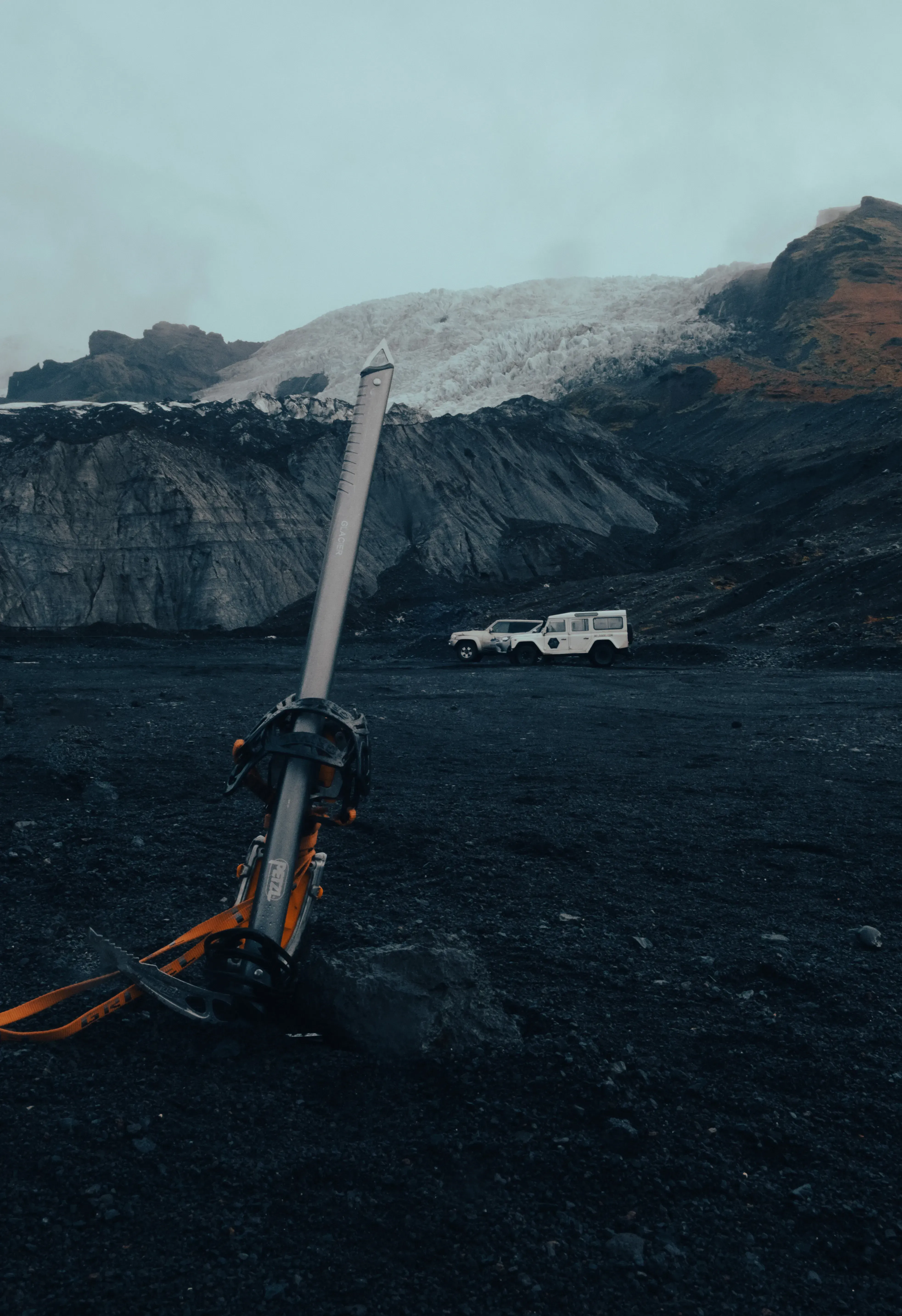 An ice axe (piolet) planted firmly in the snow or ice at the base of the Hvannadalshnjúkur glacier.