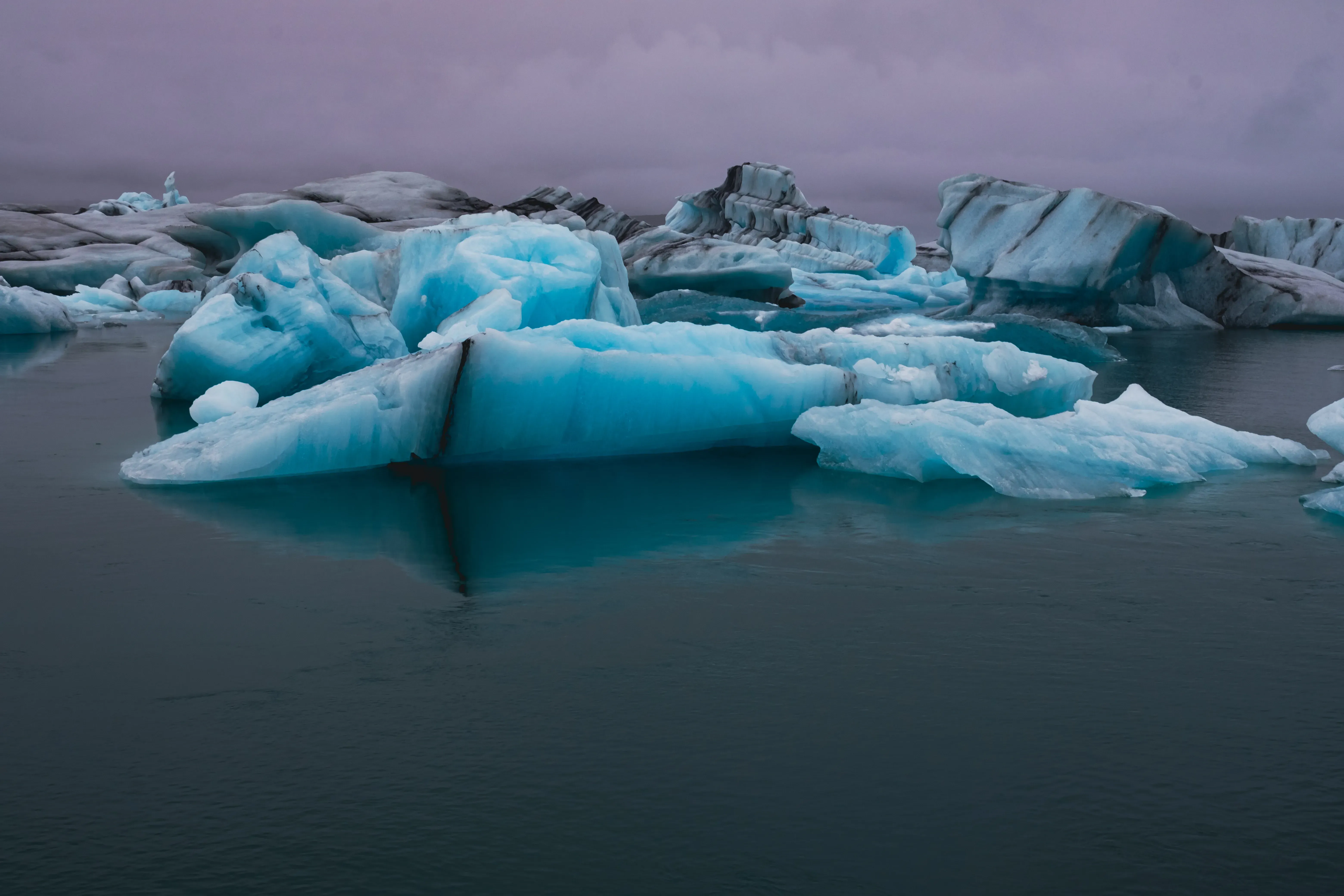 Large icebergs (glaciers) floating in the water near the shore of Diamond Beach.