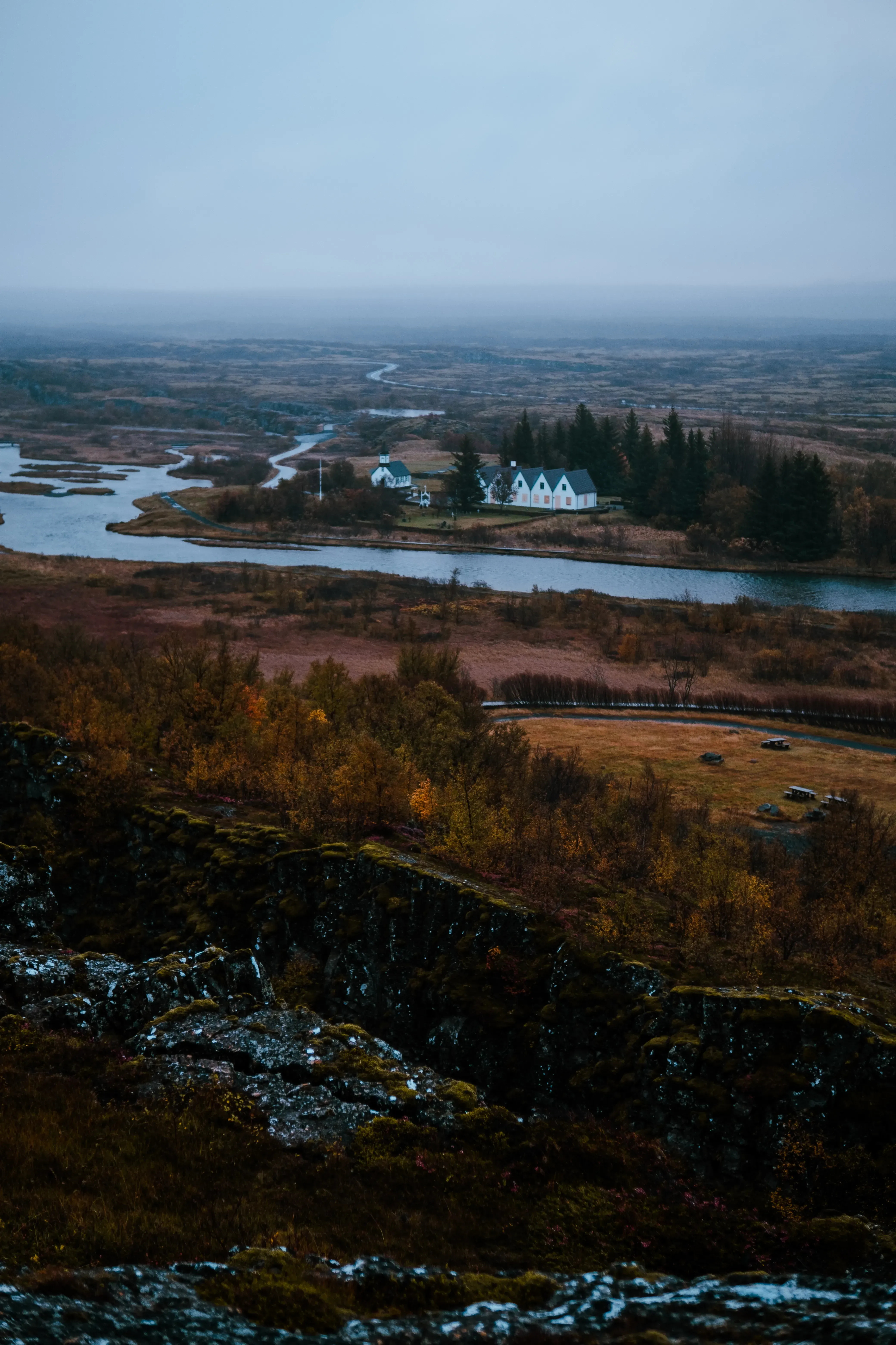 A wide river flowing through the open landscape near an Icelandic town or settlement.