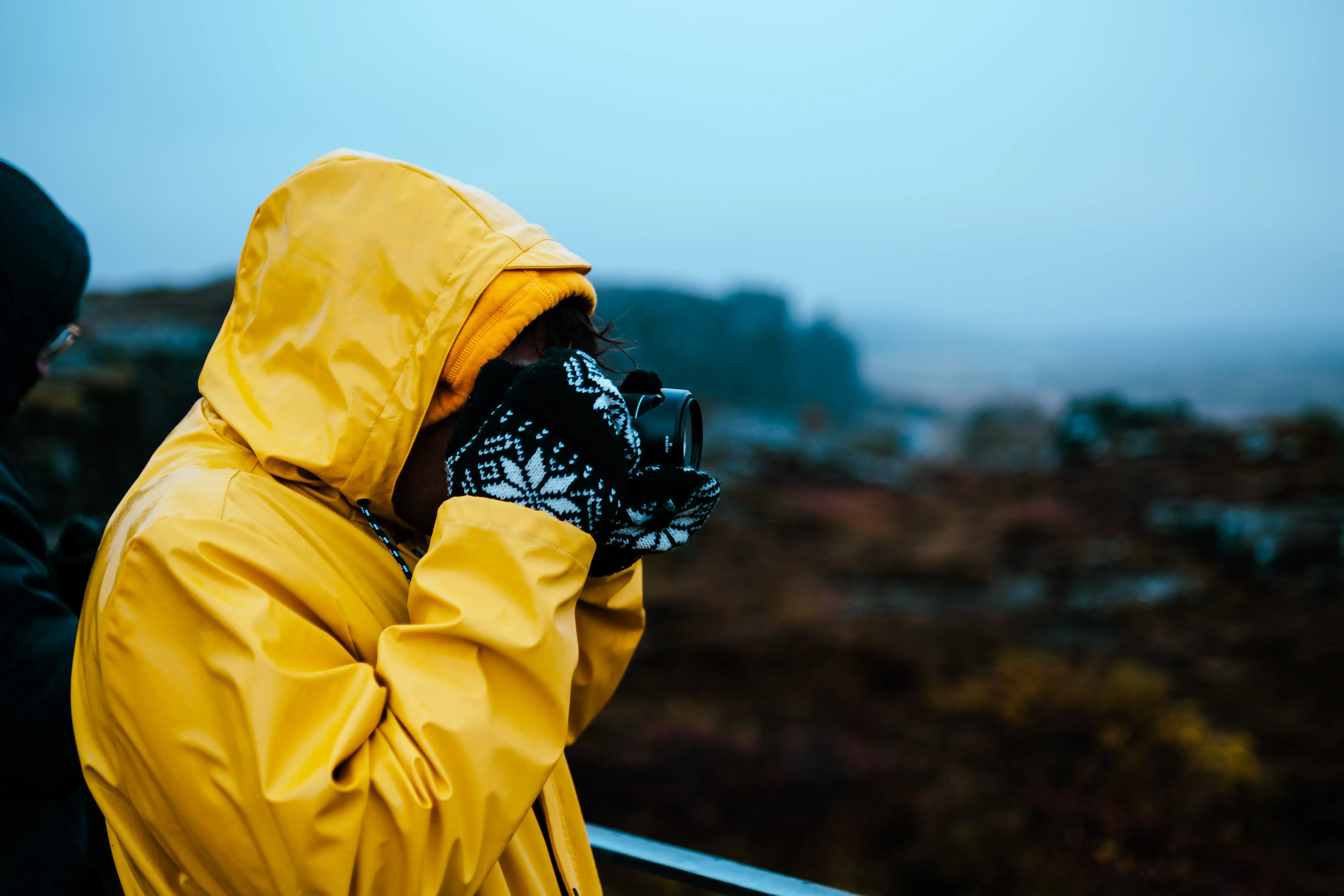 Ieser taking a photograph, shielded from rain or spray, while wearing the yellow waterproof coat.