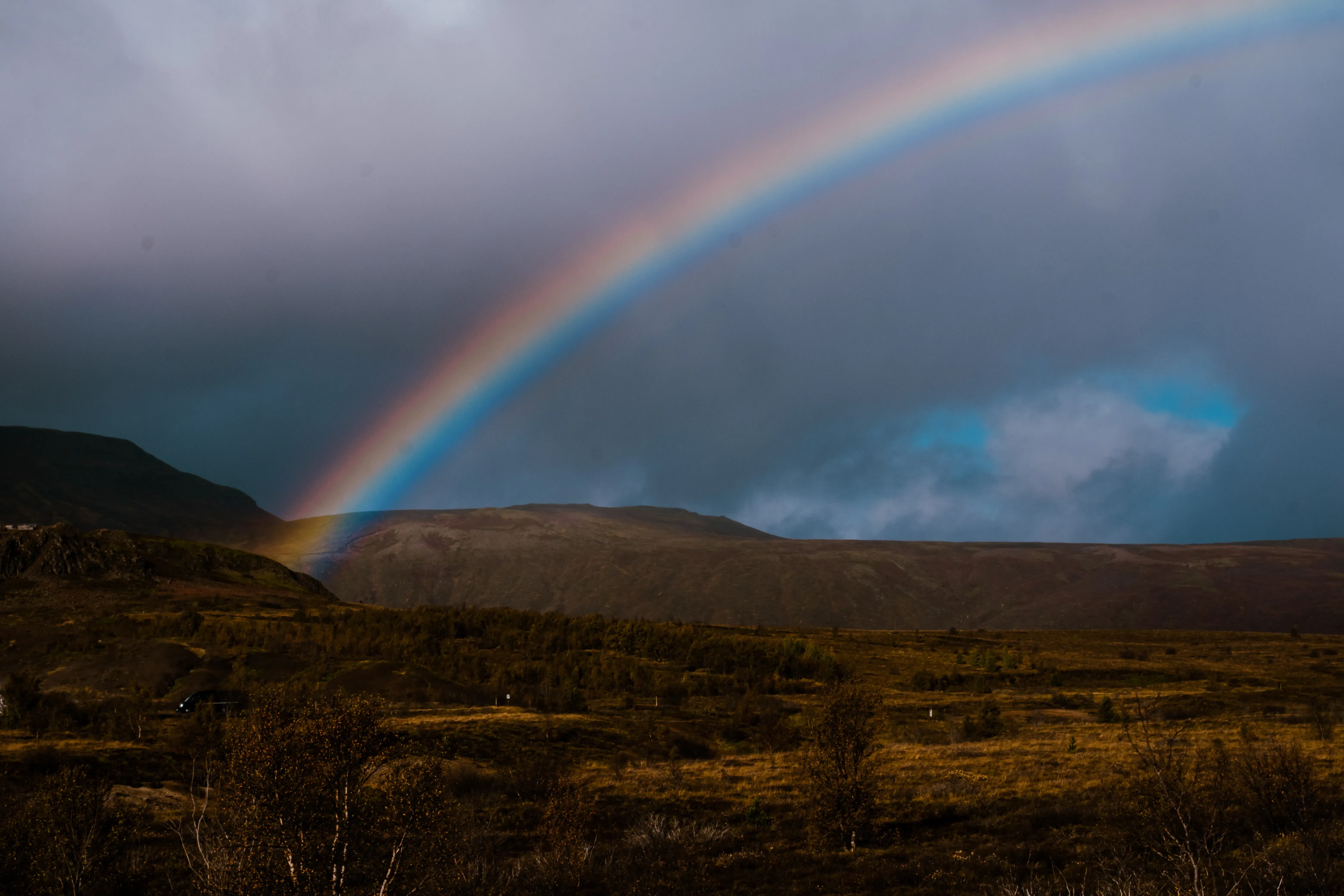 A vibrant rainbow arching over the landscape, likely caused by the spray of a waterfall or rain.