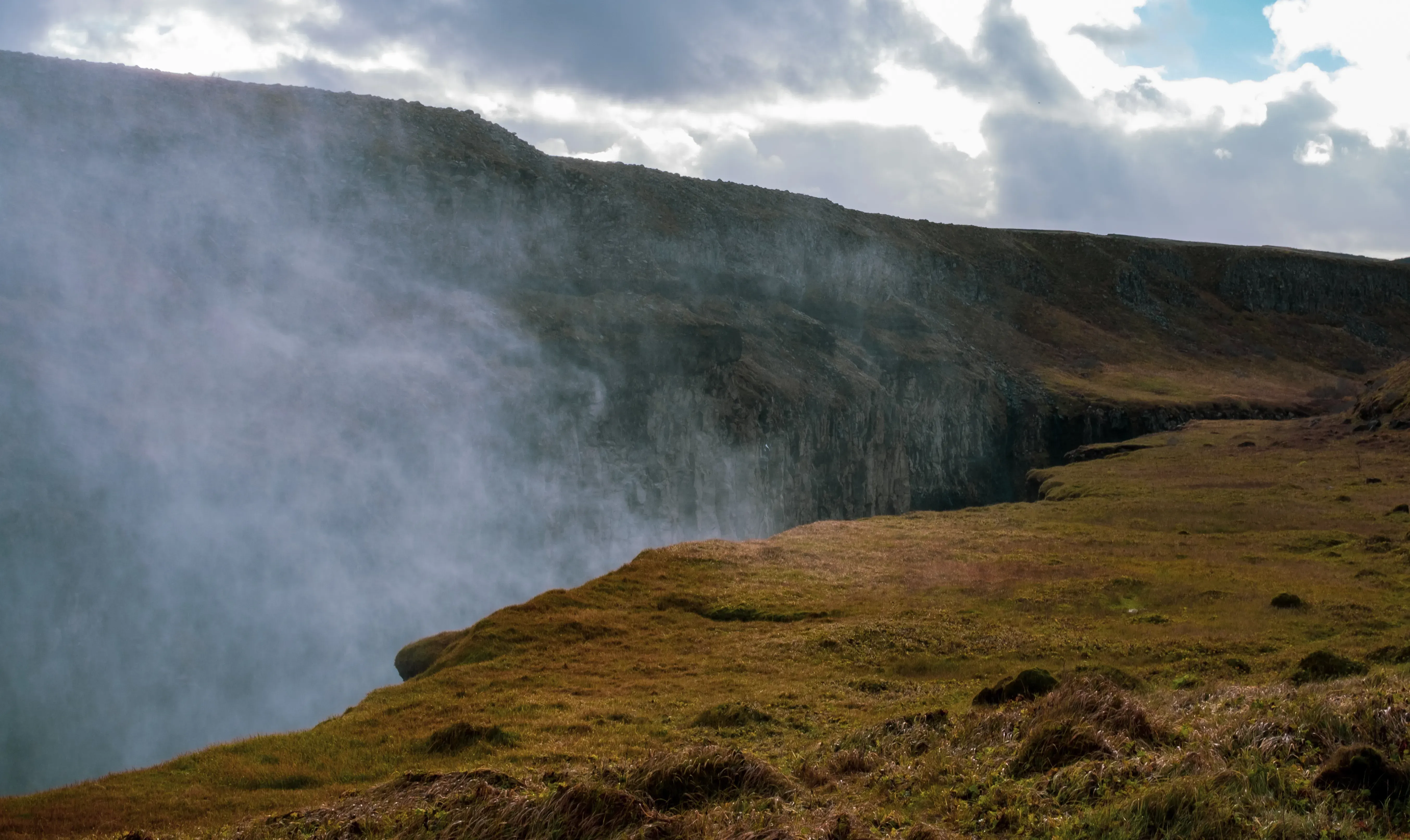 Thick columns of mist and steam rising high into the air from the crashing waters of the Gullfoss waterfall.