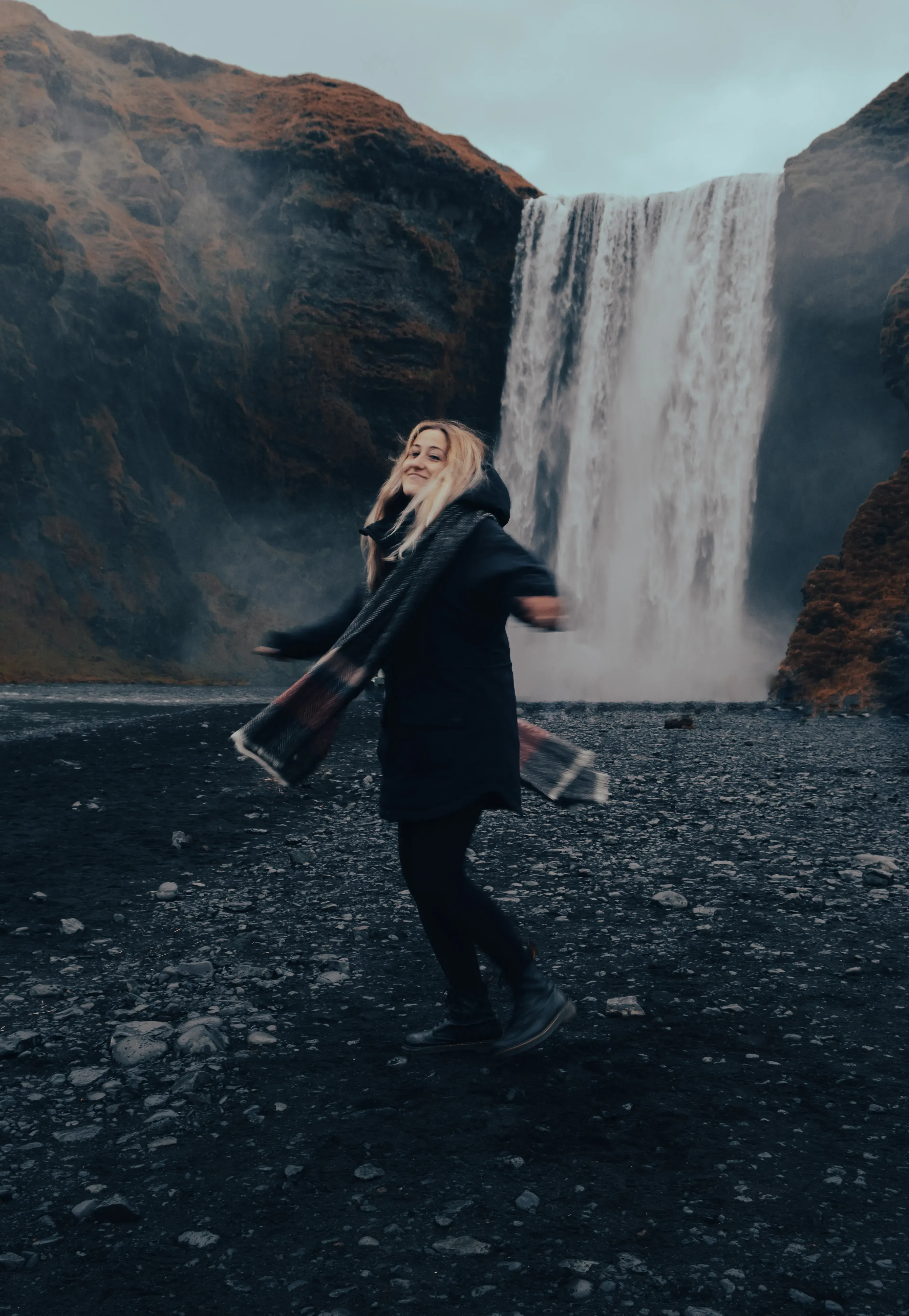 s	Letizia standing at the base of the immense Skógafoss waterfall.