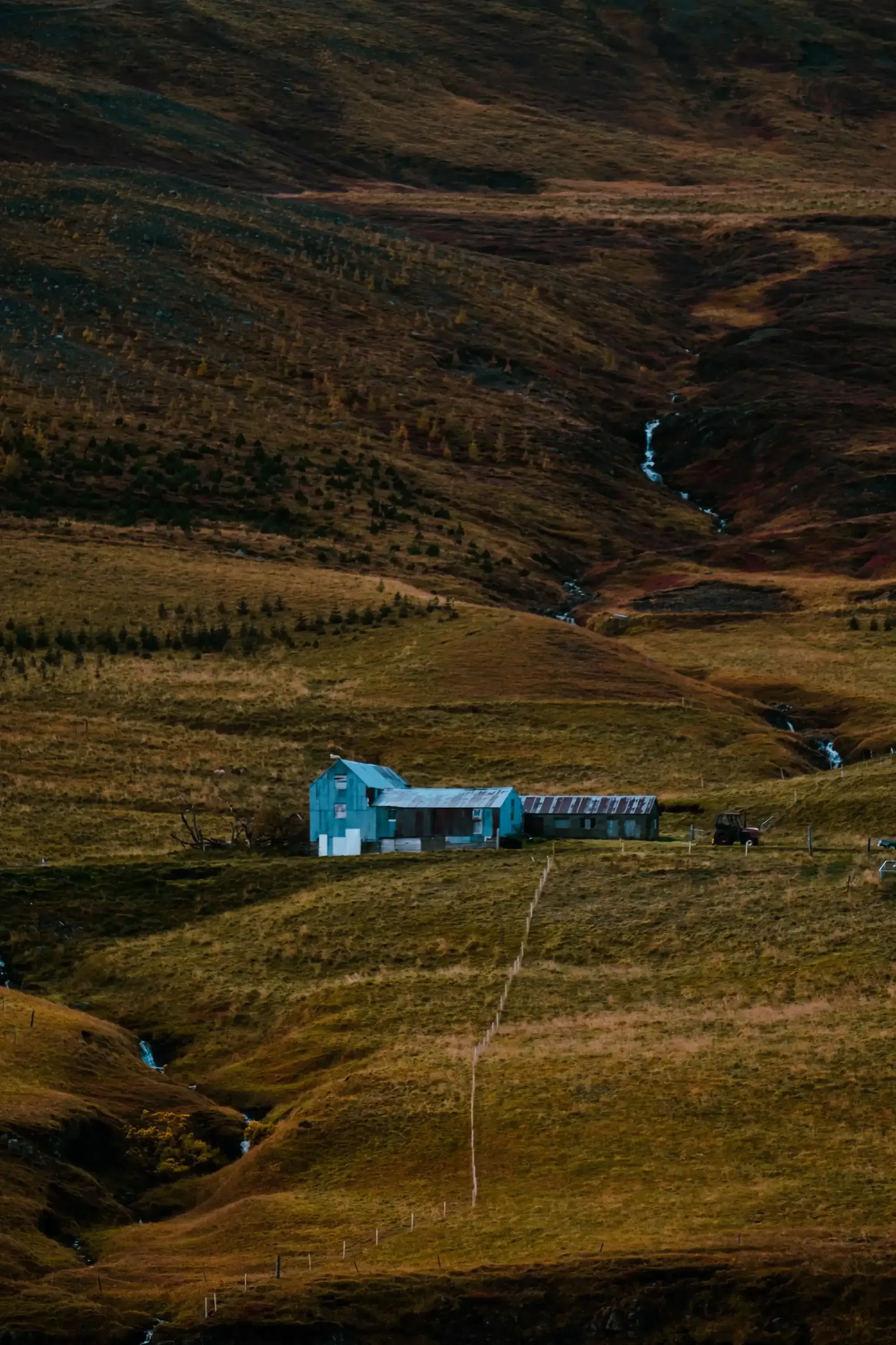 A small, traditional house situated next to a flowing stream or river in the Icelandic landscape.