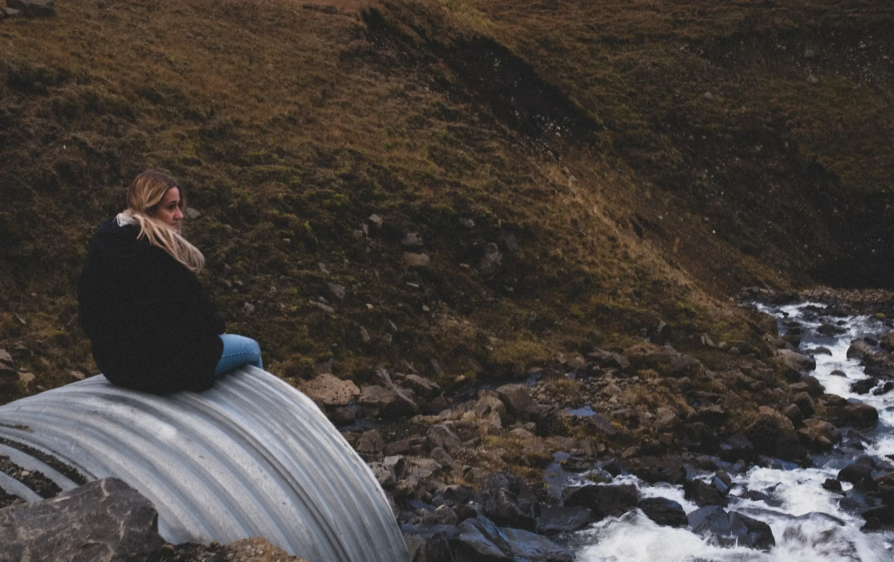 Letizia sitting on a large, exposed pipe in Iceland.