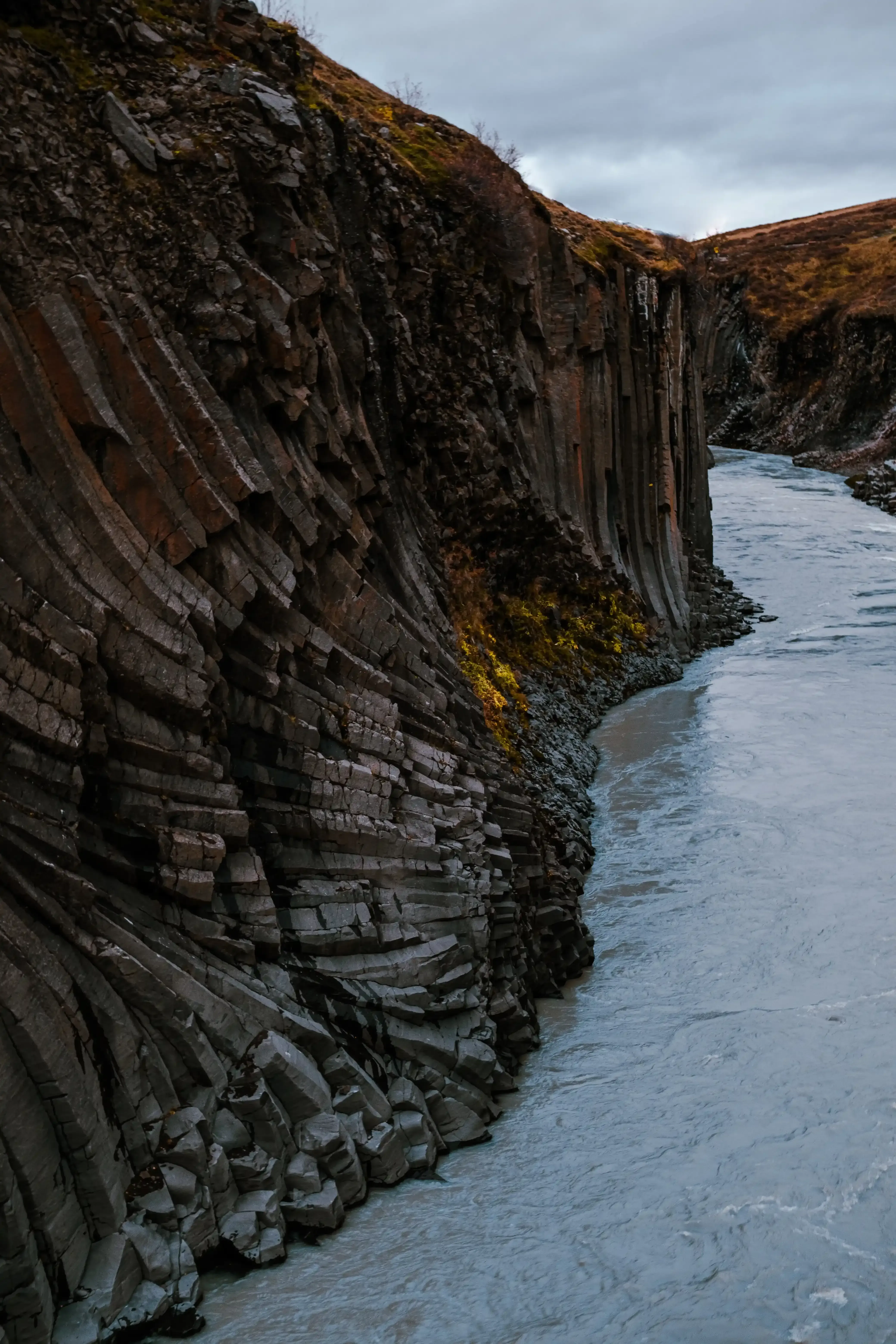 The river water near the unusual curved or bent basalt column formations in Stuðlagil.