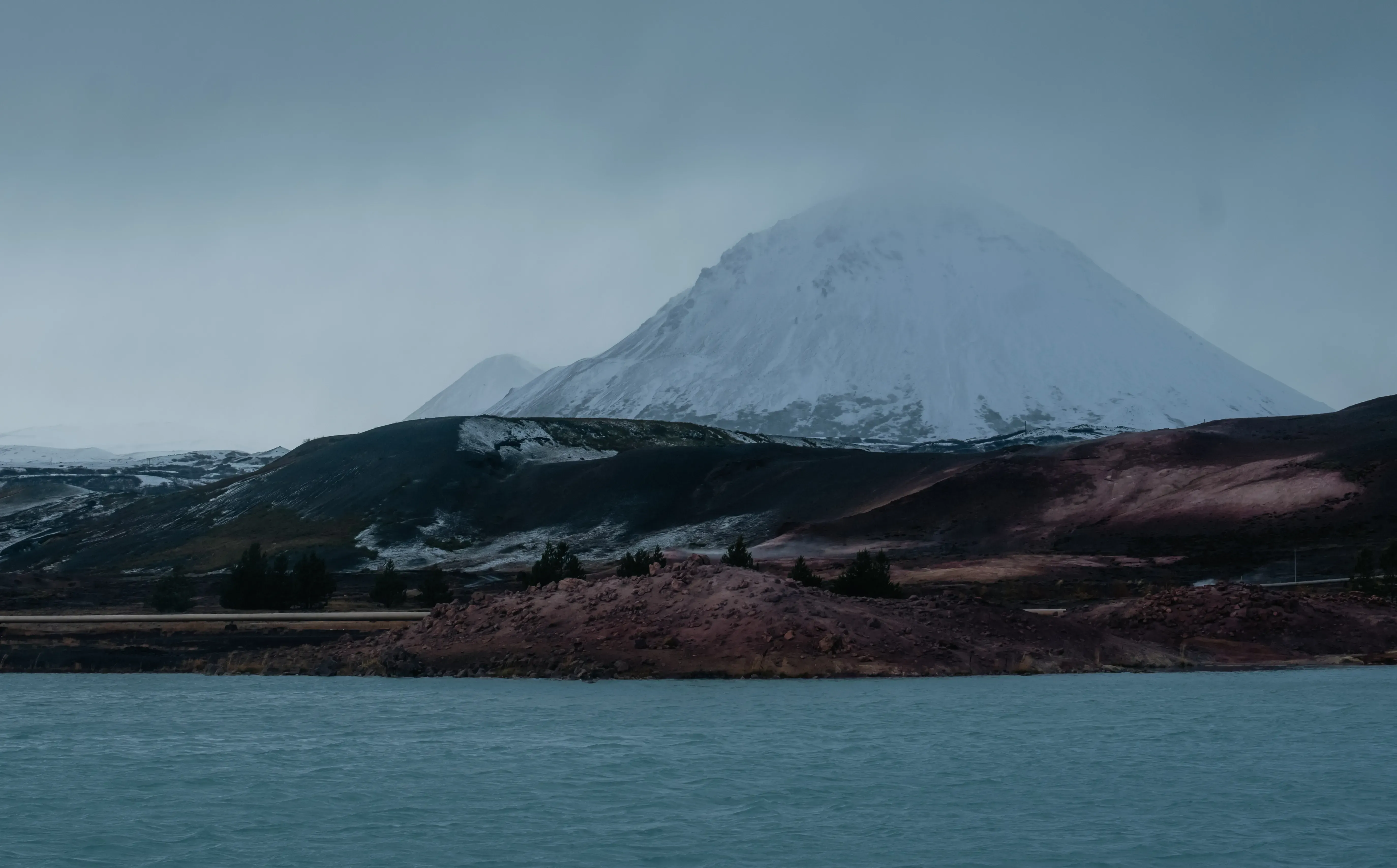 A snow-capped mountain positioned close to the coast or the ocean.