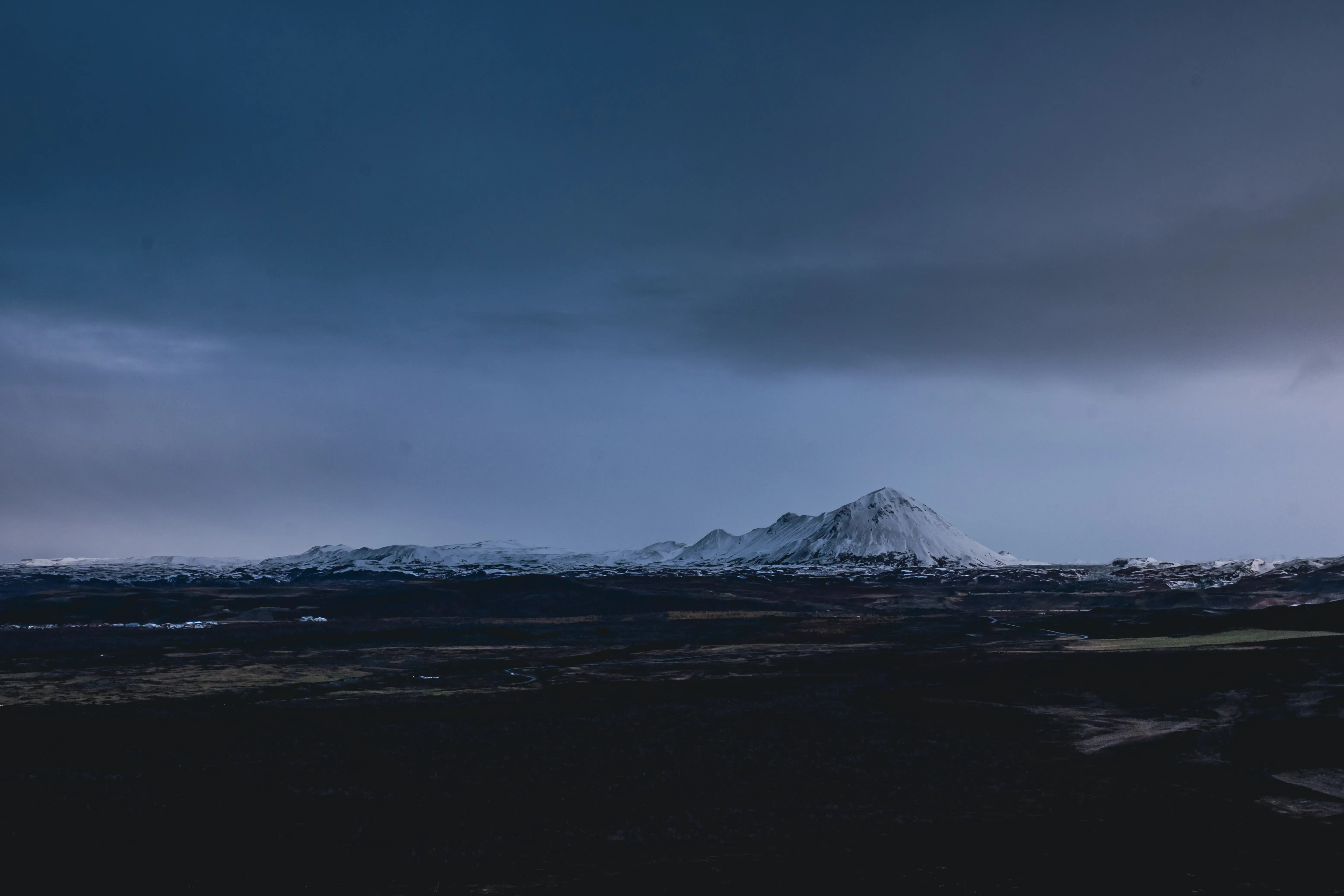 A wide, atmospheric view of the characteristic landscape of Iceland (mountains, lava fields, or moss).