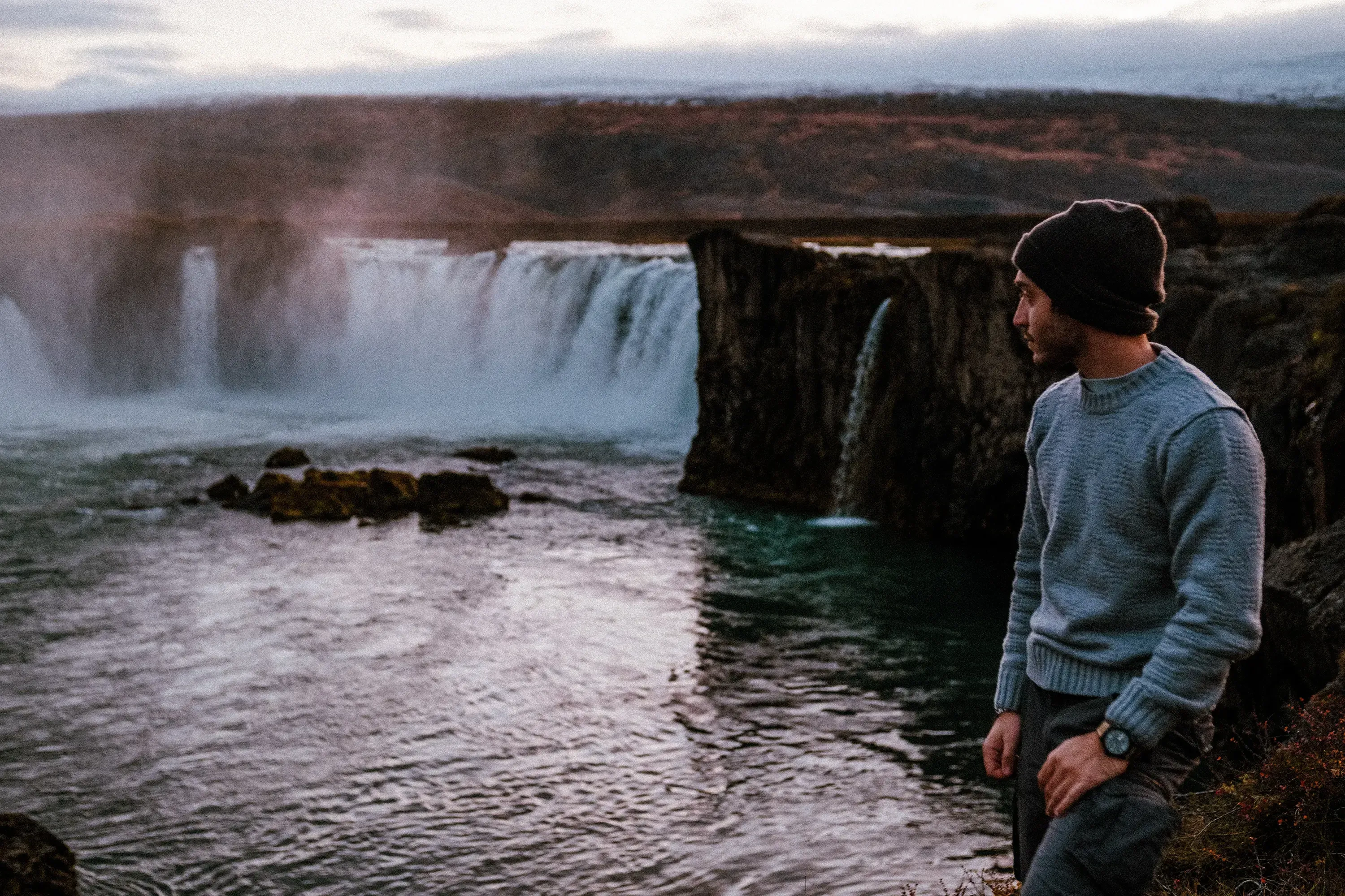 Stefano standing near the viewing area in front of the horseshoe-shaped waterfall (e.g., Godafoss)