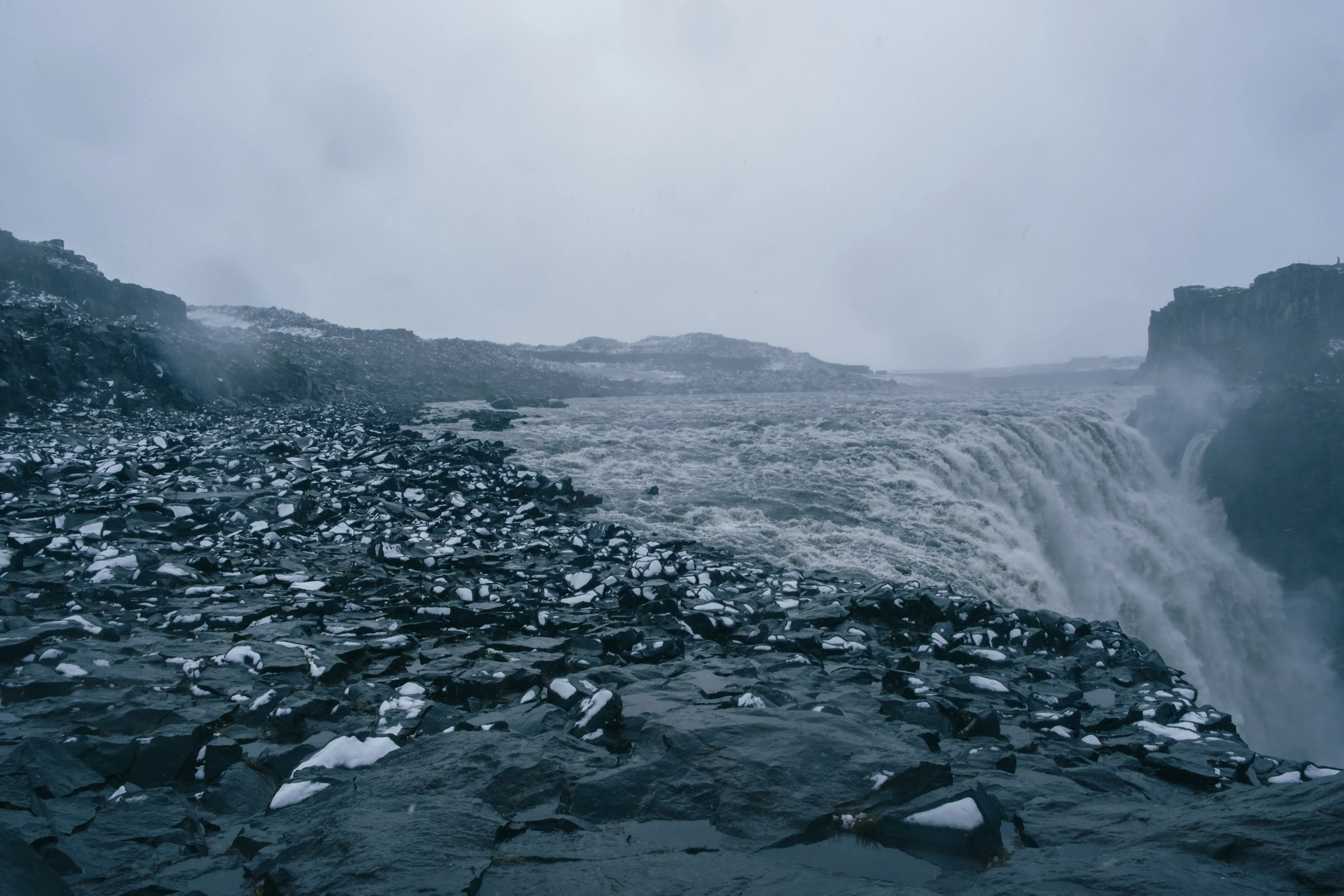 The immense Dettifoss waterfall during winter, surrounded by snow and ice.