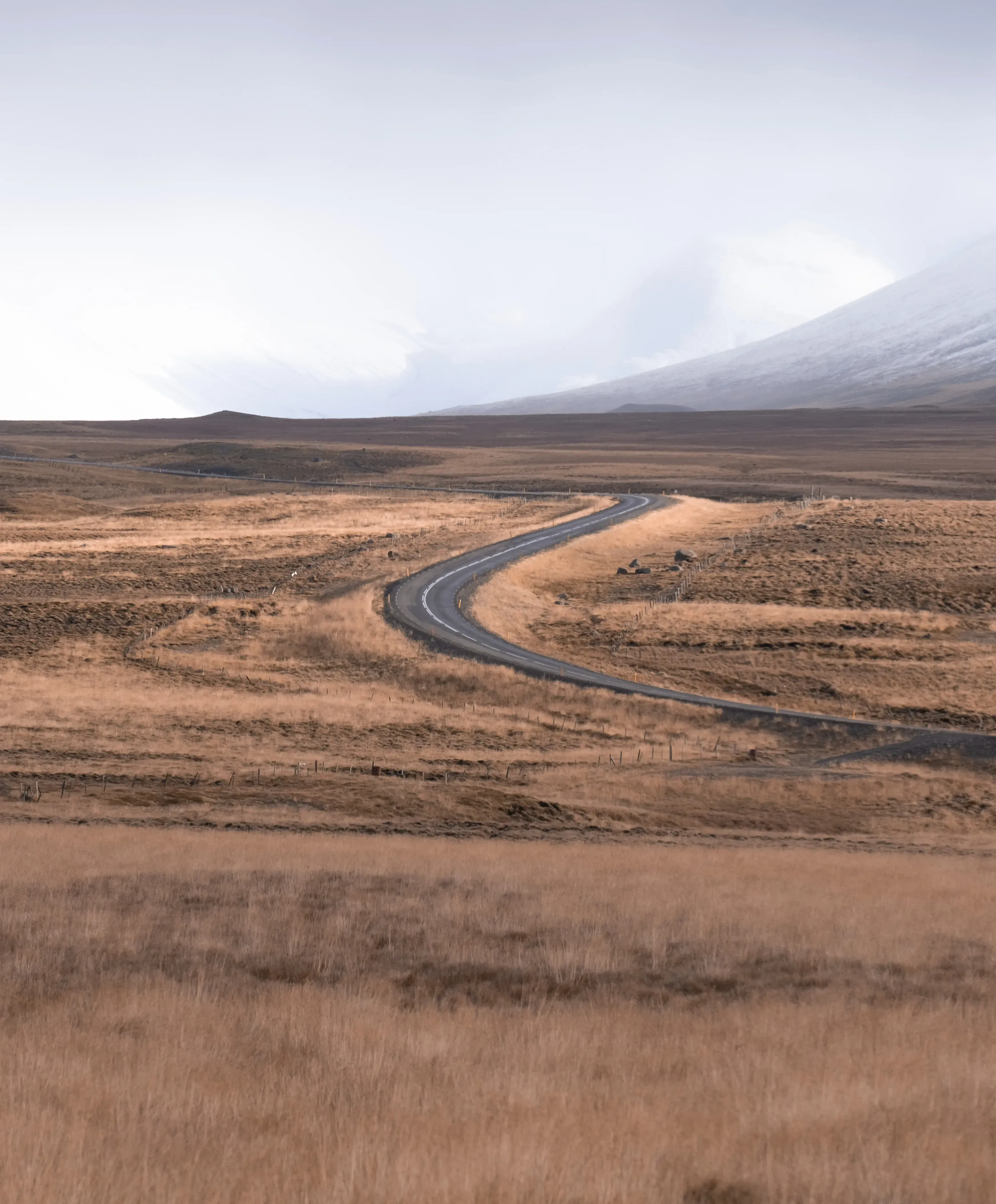 A road cutting through the vast, sparsely vegetated steppe or highlands of Iceland.