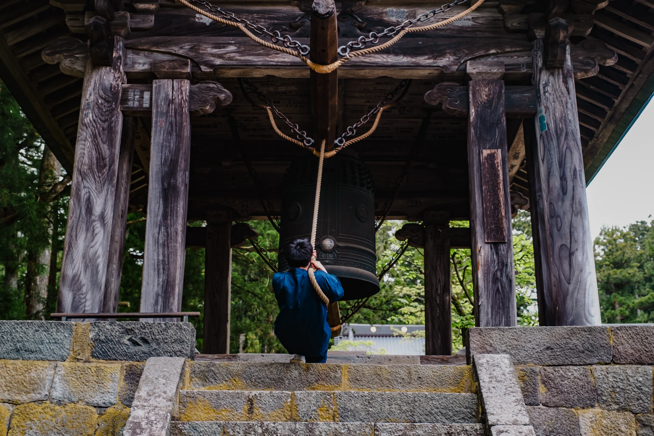 A boy ringing a large temple bell at a shrine in Nikko