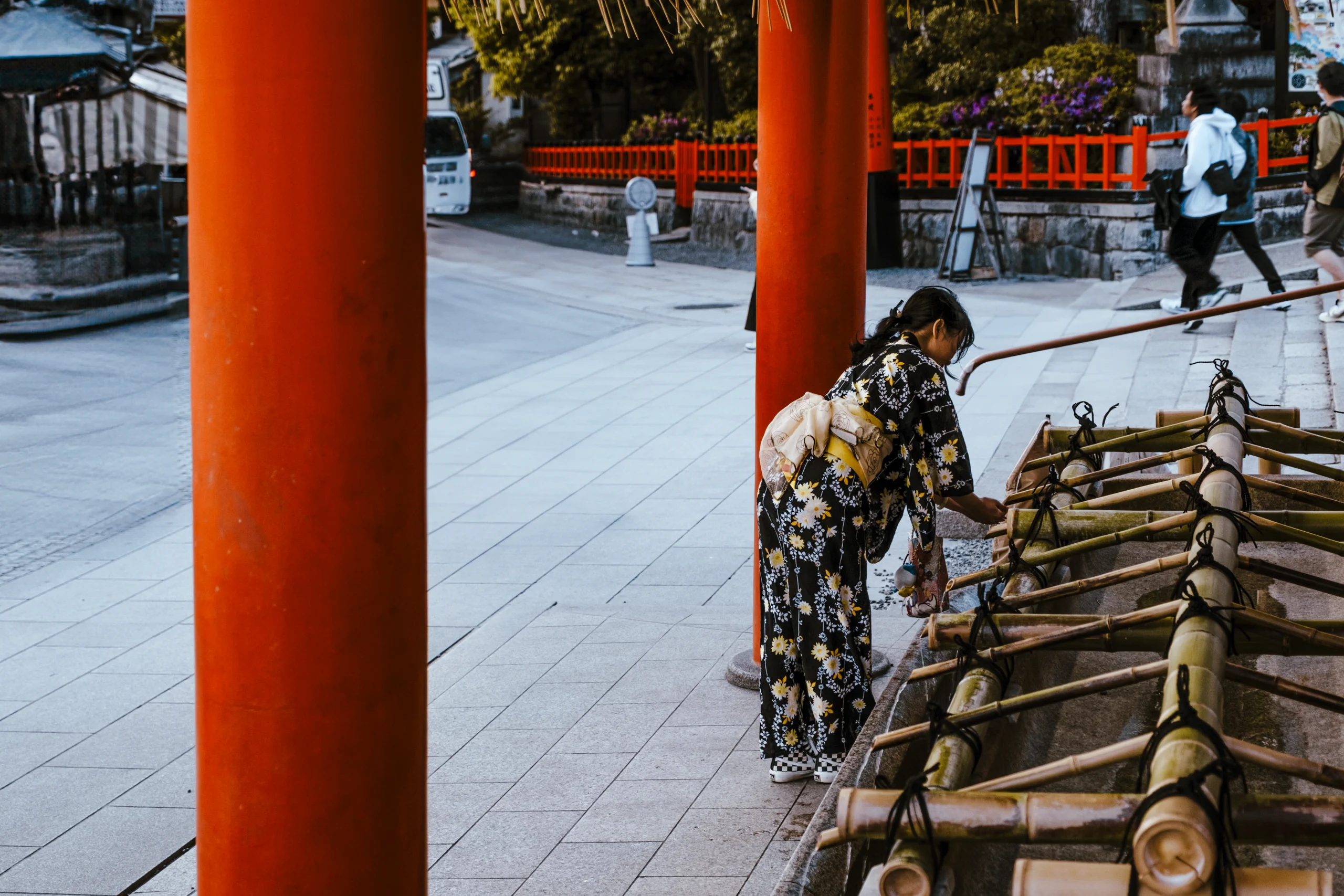 Young woman purifying hands at a Chozuya water pavilion near Torii gates in Kyoto