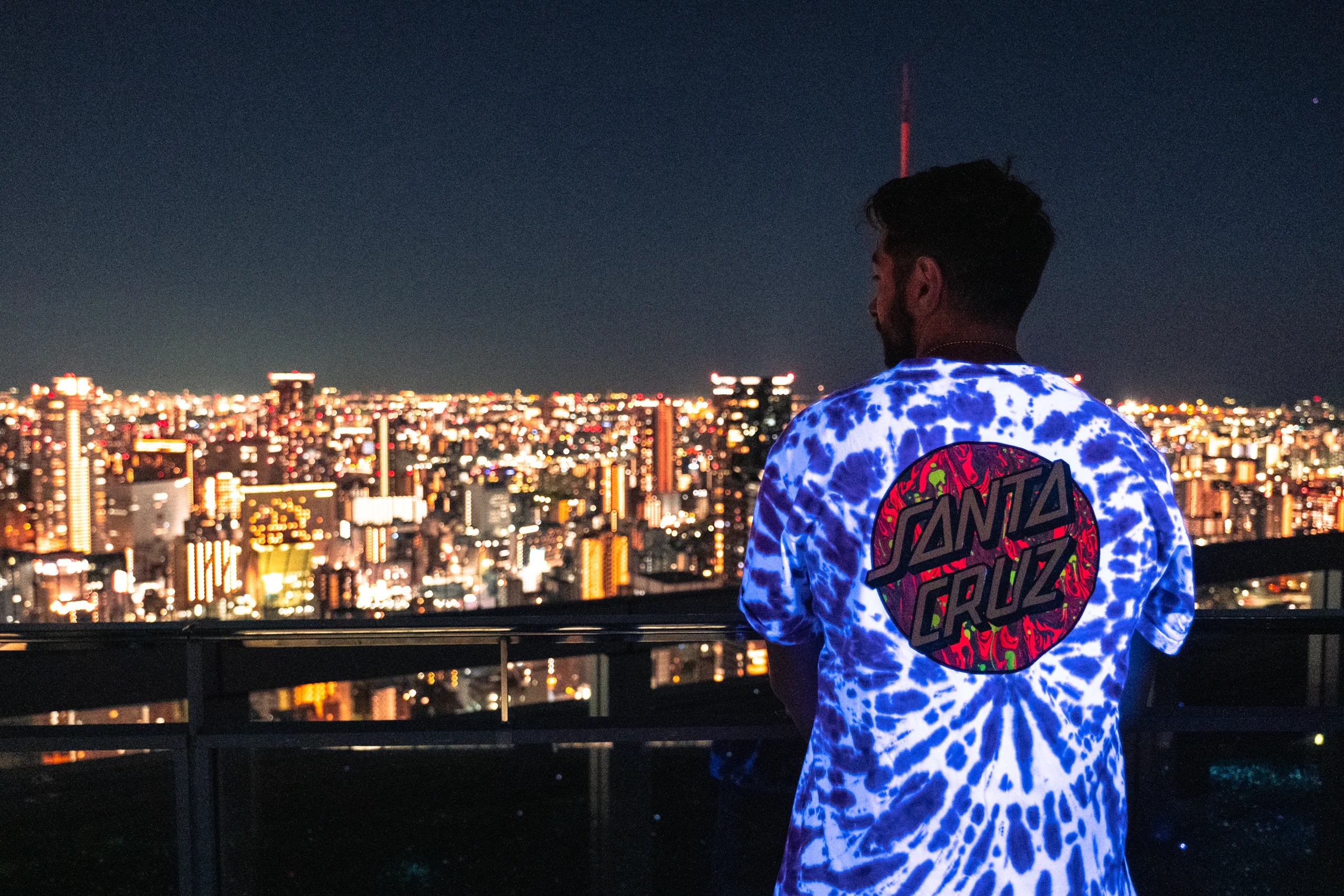 Iair posing in front of the illuminated Osaka city skyline at night