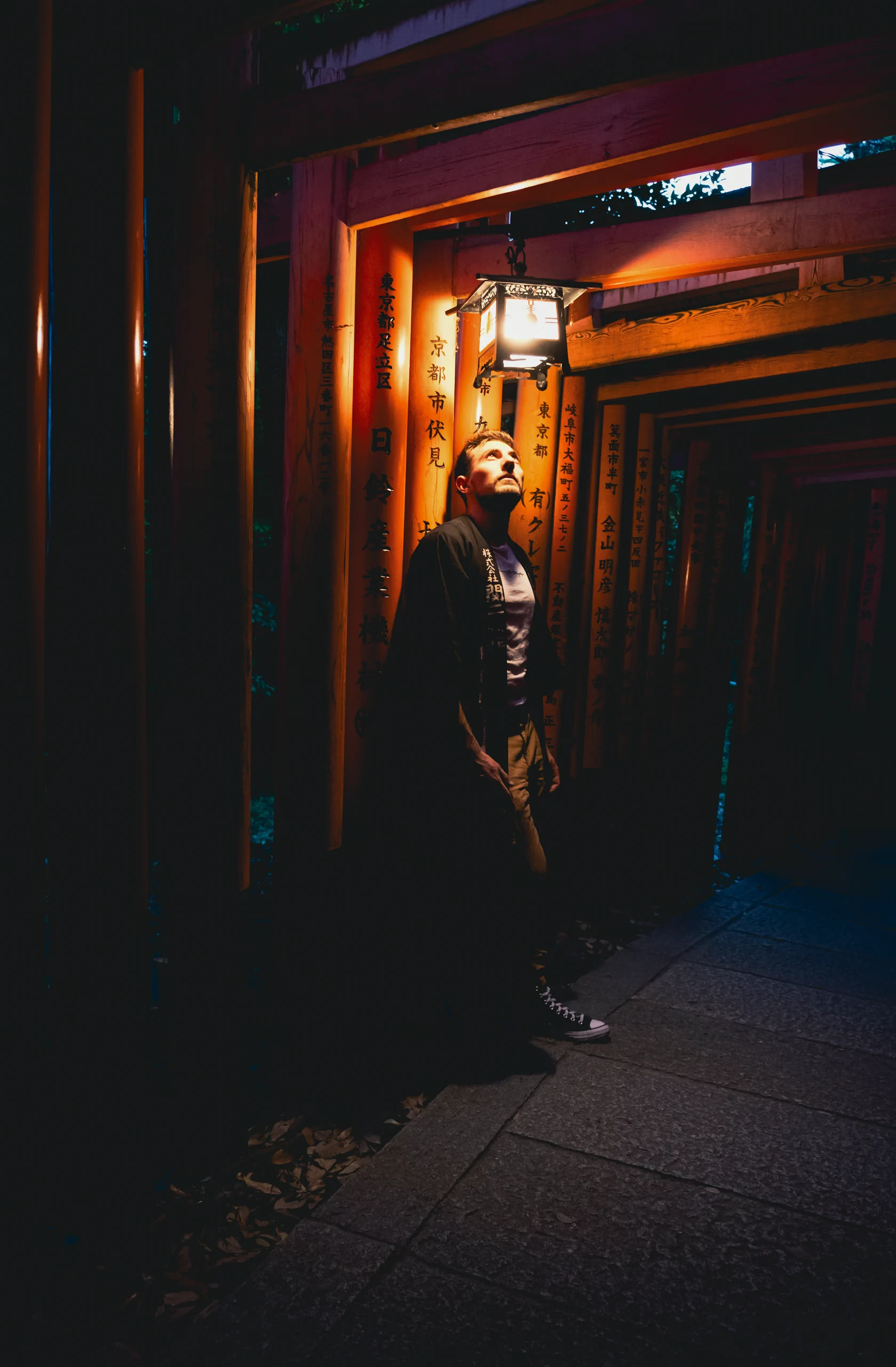 Davide standing among the red torii gates at Fushimi Inari Shrine in Kyoto at night