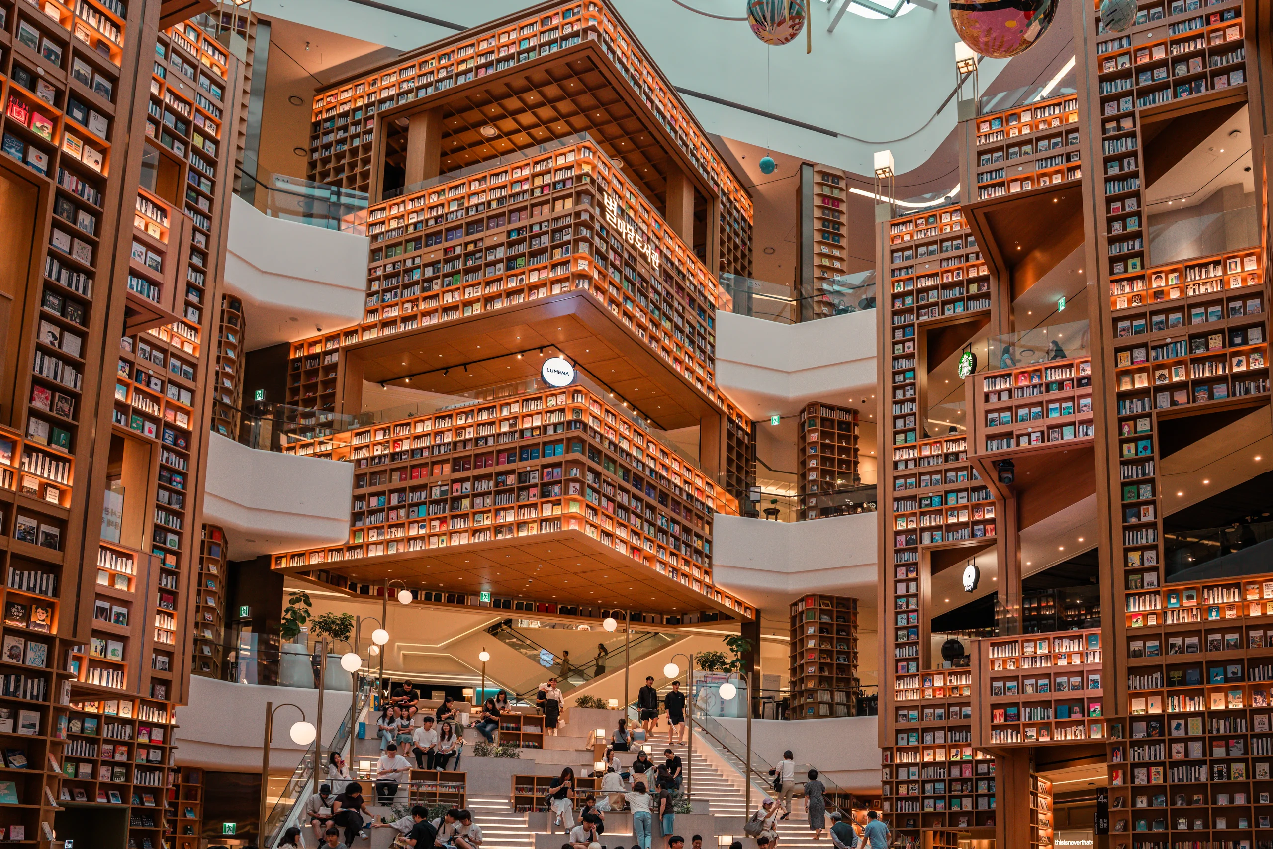 Wide angle shot capturing the towering, curved bookshelves of Starfield Suwon Library from the ground floor.