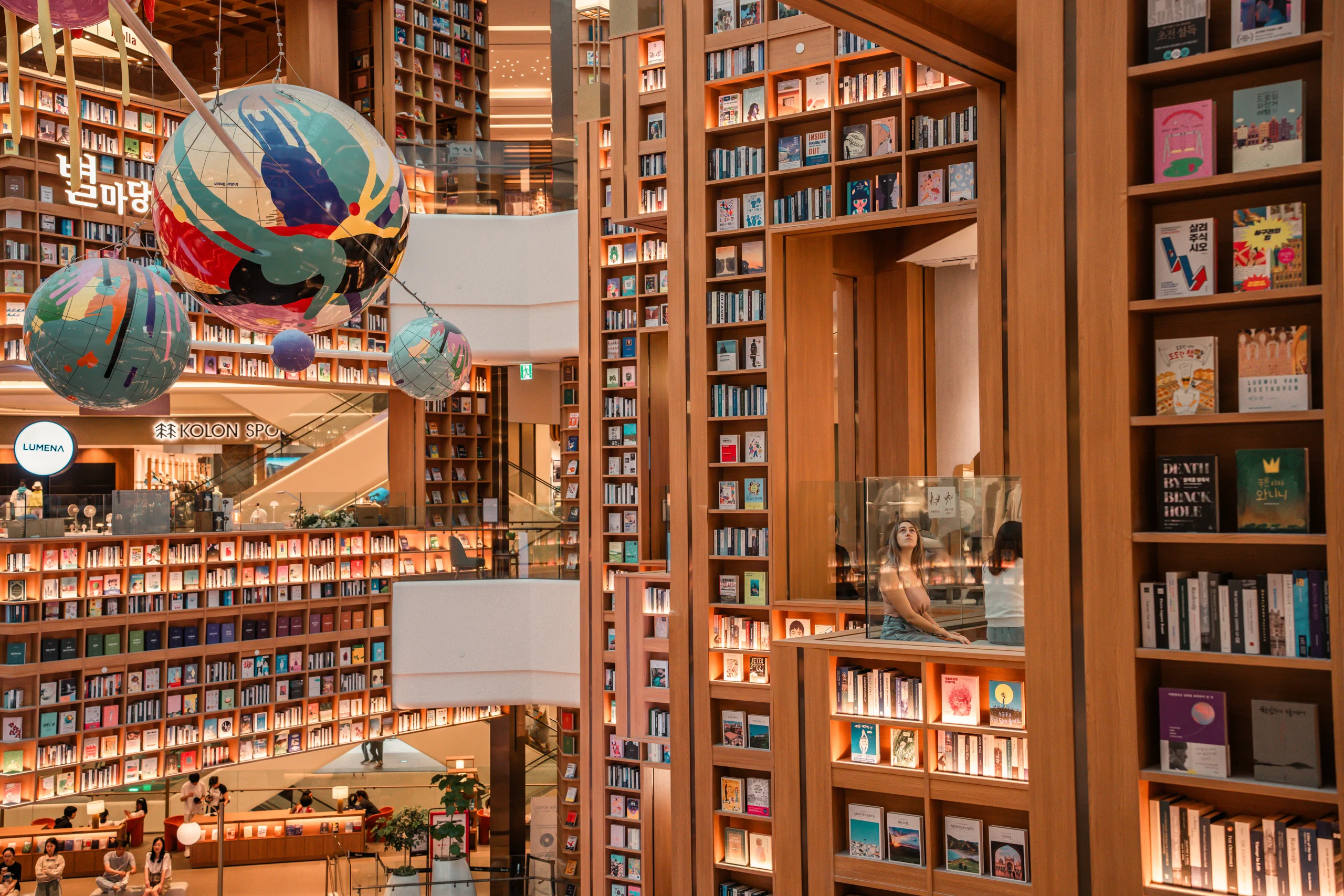 Letizia standing next to the enormous, packed bookshelves in the Starfield Suwon library.