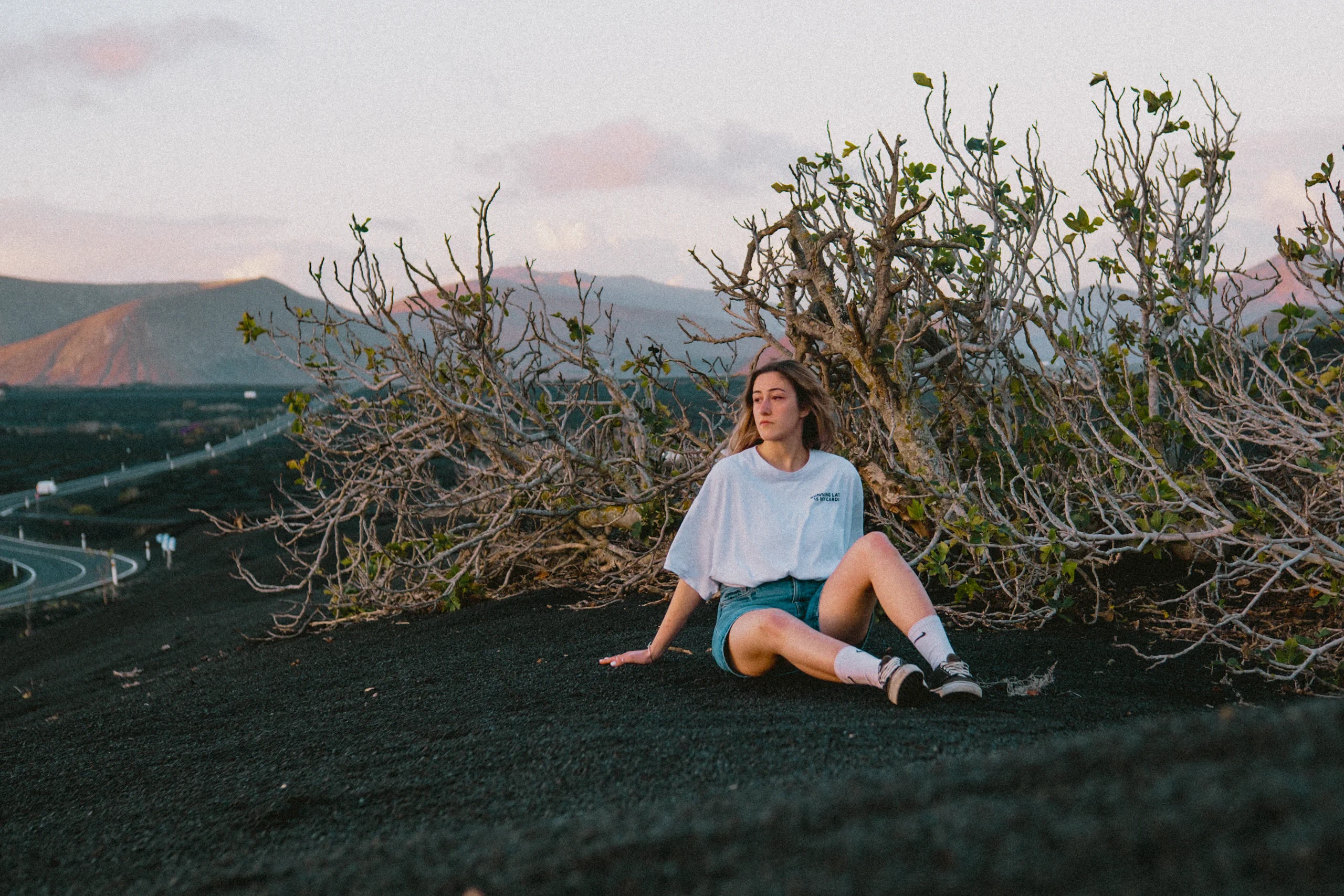 Letizia sitting in a traditional vineyard in La Geria, Lanzarote, featuring the characteristic black soil and stone windbreaks.