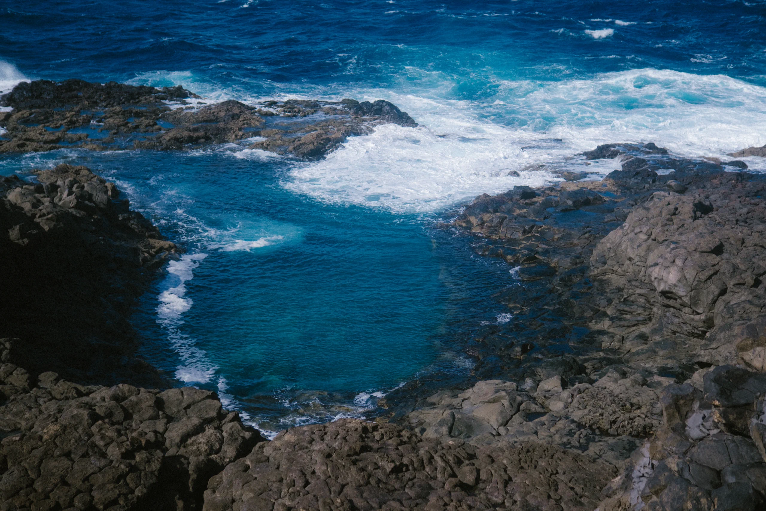 Natural tide pools formed in the volcanic rock along the coast.