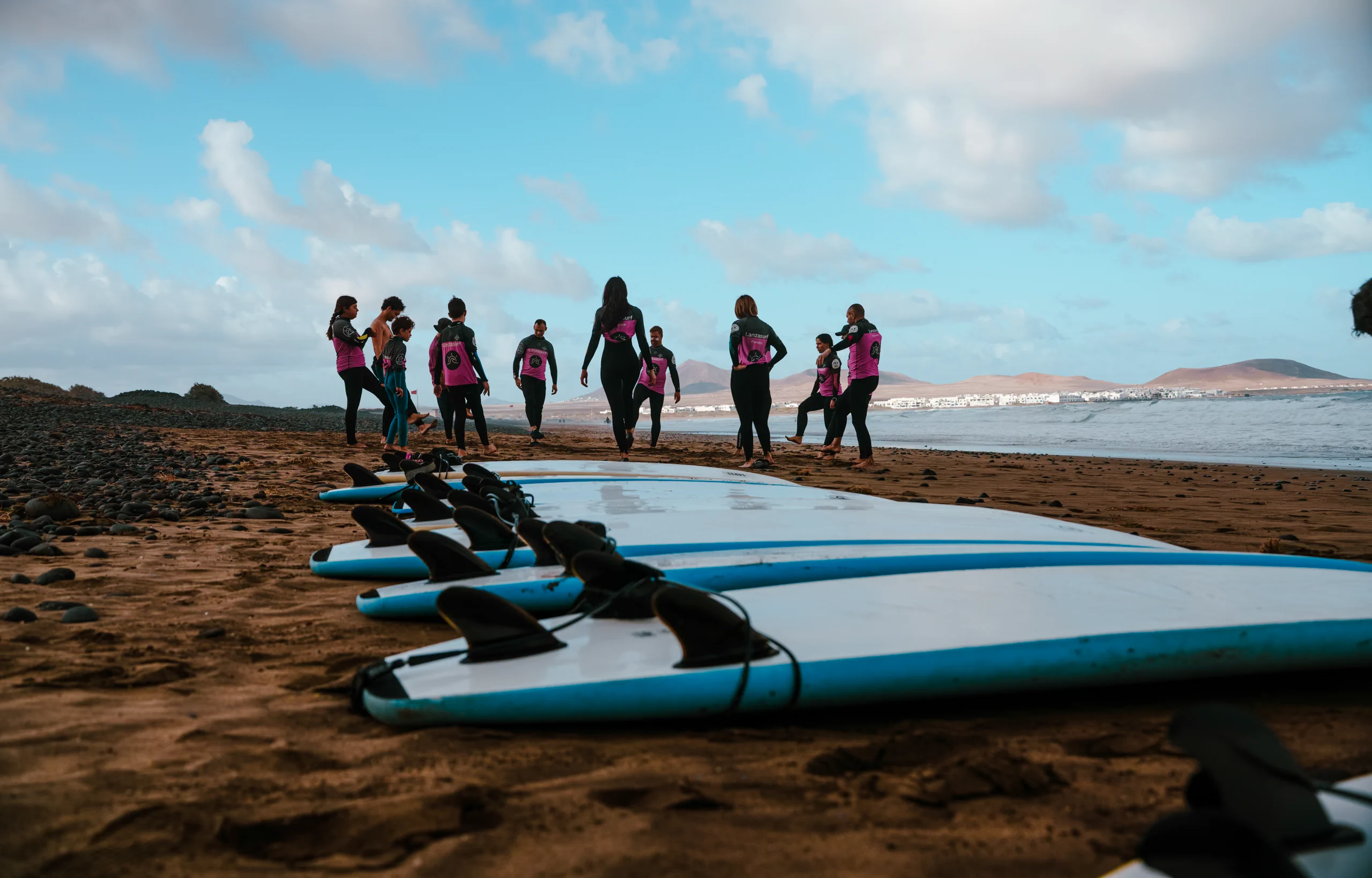 The surfboard on the Famara beach, while people is duing stretching in the back