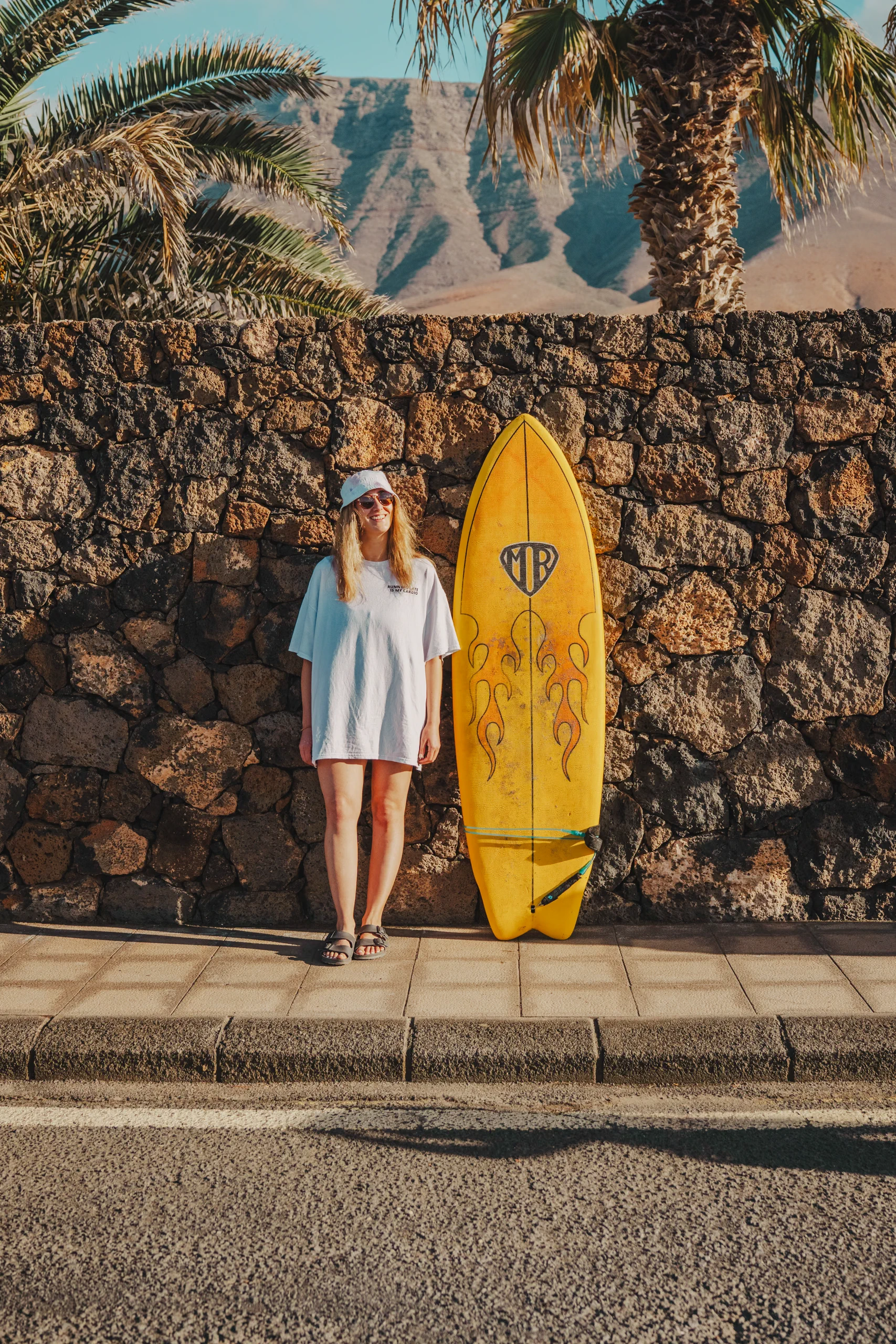 Letizia posign next to a wall next to a yellow surf board