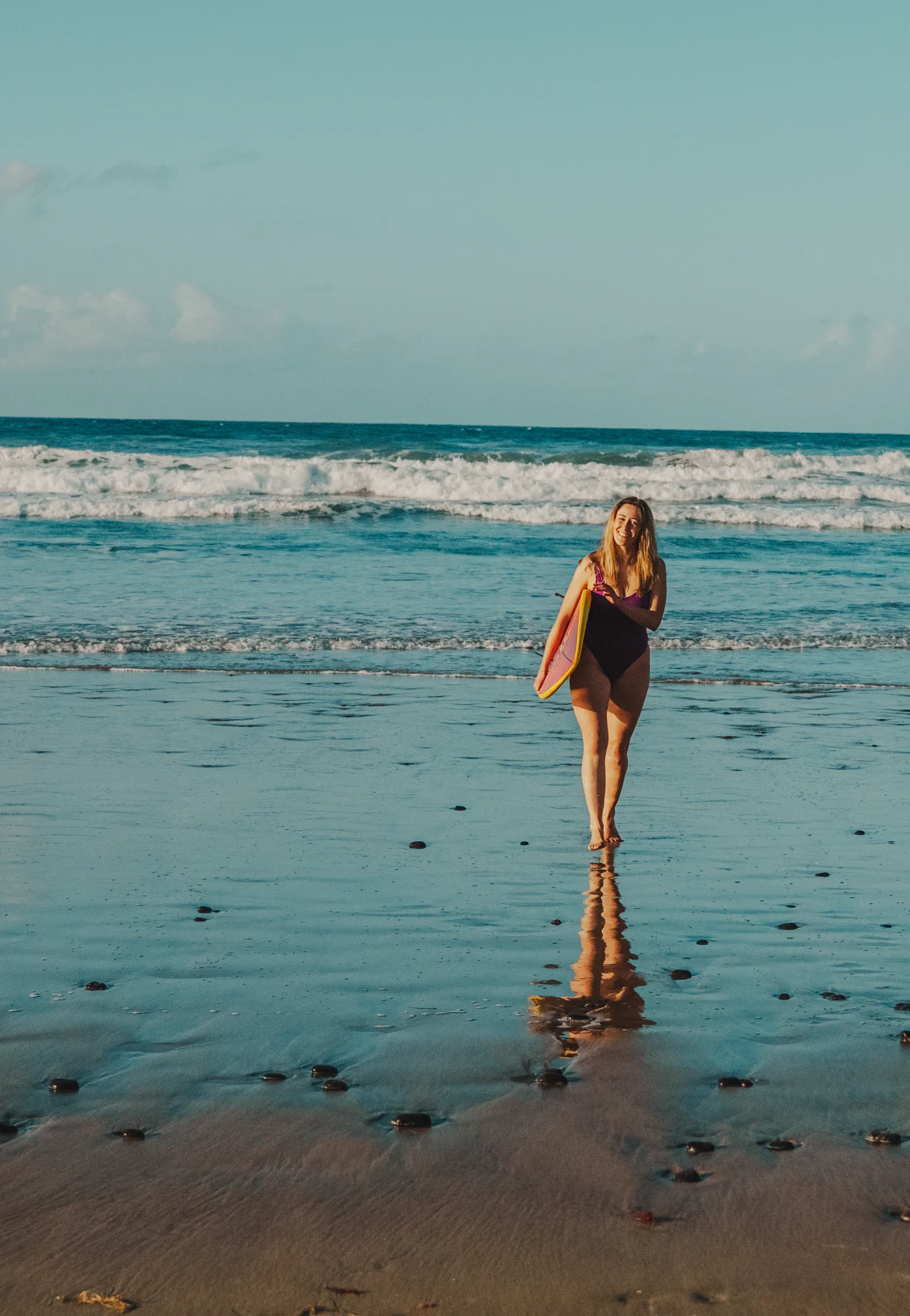 Letizia walking on the beach with a surf board