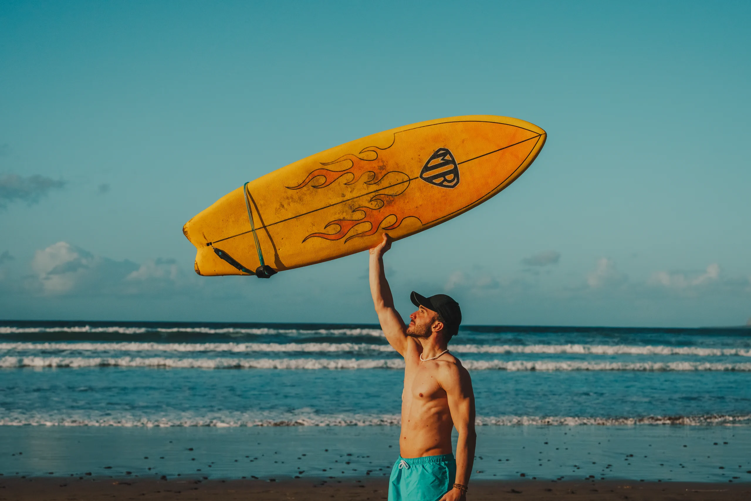 Stefano holding a surf board with one hand in Famara beach