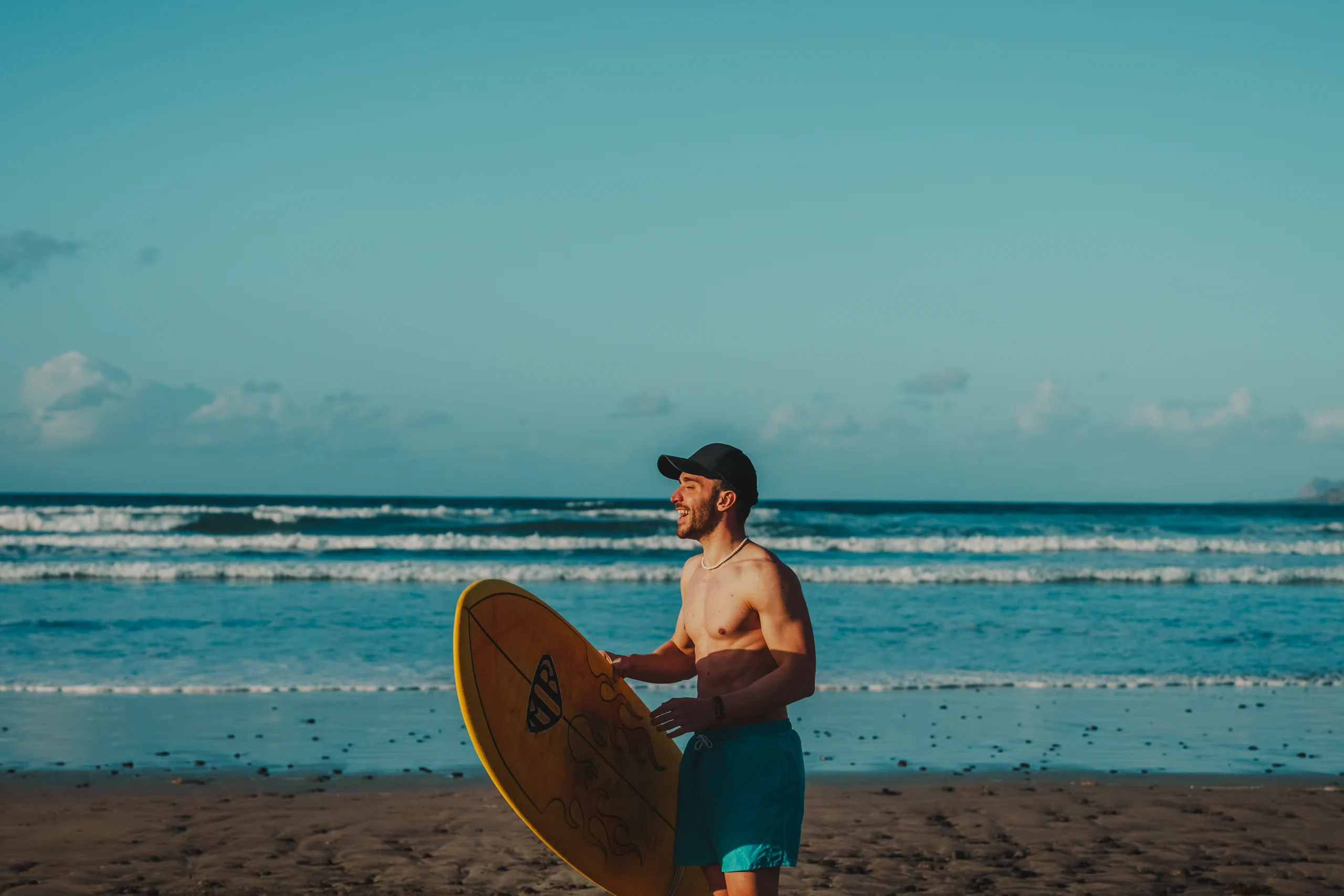 Stefano smiling with his surf board on Famara beach