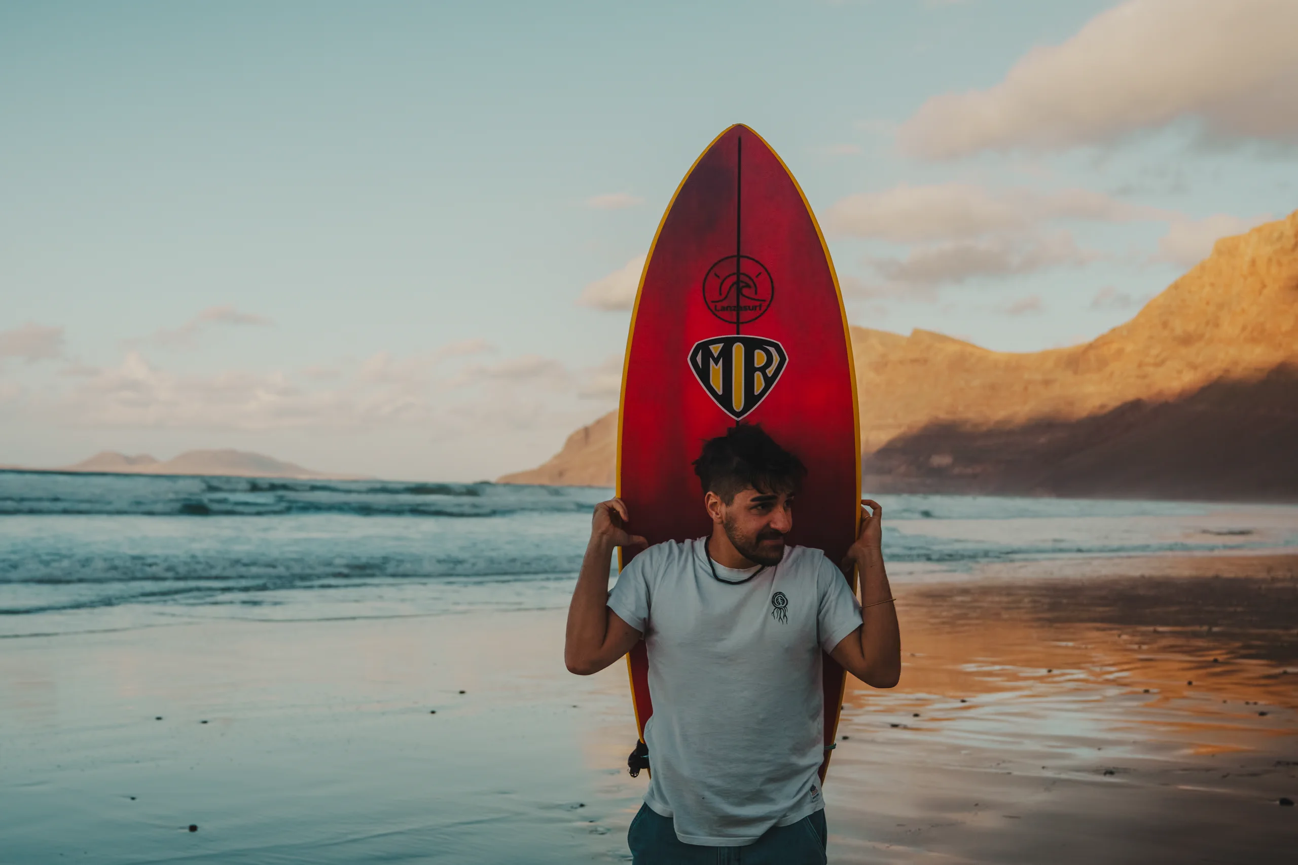 Ieser with a board over his shoulders in Famara beach